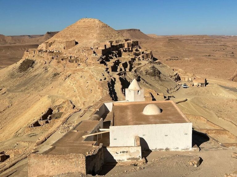 Guermassa Tataouine sud Tunisie est l'un des plus beaux villages-citadelles de la région du Dahar. Perché entre 450 et 500 mètres d'altitude, il se déroule sur 17 hectares sur la crête et la colline du Djebel Kedim. Guermassa est un village troglodytique parfaitement intégré dans son environnement naturel. Organisé en rangées de maisons troglodytiques latérales creusées entre les couches géologiques et utilisant les matériaux de leurs roches, il est en parfaite harmonie avec la morphologie et la géologie de la montagne qu'il occupe. Le village est riche de plusieurs composantes patrimoniales typiques du Dahar : un ksar citadelle à son sommet (dont il ne reste que des ruines) appelé galla, un ksar destiné au stockage des récoltes, une mosquée datée de 1860, une huilerie, des habitations troglodytiques en nombre et même une nécropole. A pied, le tour complet du village nécessite au moins une heure, et nous vous conseillons de réaliser cette visite !