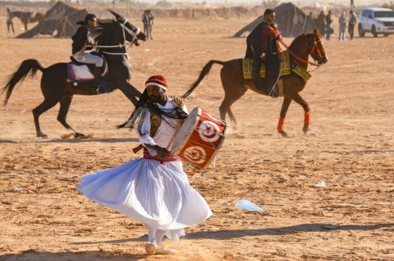 Découvrez l'Exaltation du Festival de Douz dans le Sud de la Tunisie Le festival de Douz, une célébration vibrante au cœur du sud de la Tunisie, est bien plus qu'un simple événement. C'est une expérience immersive qui vous transporte au cœur de la culture riche et de la joie contagieuse de la région. Dans cet article, nous vous plongeons dans l'univers enivrant du festival de Douz, en vous dévoilant tout ce que vous devez savoir pour vivre une aventure inoubliable. L'Effervescence Culturelle au Festival de Douz Le festival de Douz, connu également sous le nom de Festival des Dattes, est une explosion de couleurs, de danses, de musiques et de traditions. Chaque année, des milliers de visiteurs affluent vers cette petite ville du sud de la Tunisie pour participer à cette célébration unique. Des costumes traditionnels chatoyants aux rythmes envoûtants des tambours, l'effervescence culturelle vous enveloppe dès votre arrivée. Un Voyage au Cœur du Désert Le festival de Douz se déroule au beau milieu du désert, ajoutant une touche encore plus spéciale à l'événement. Les dunes de sable doré offrent un cadre pittoresque et enchanteur pour les festivités. Vous pourrez vous perdre dans les ruelles du marché coloré, où des échoppes offrent des trésors artisanaux uniques, des tapis tissés à la main aux bijoux traditionnels. Une immersion totale dans la culture saharienne vous attend. Spectacles Époustouflants et Compétitions Captivantes Le point d'orgue du festival est le spectacle de fantasia, une démonstration équestre époustouflante qui met en avant l'adresse et la maîtrise des cavaliers. Les chevaux lancés au galop, les costumes traditionnels et les tirs de fusils en l'air créent une ambiance électrisante. De plus, ne manquez pas les compétitions de course de chameaux, où ces majestueux animaux rivalisent dans des courses passionnantes. Gastronomie et Saveurs Uniques Le festival de Douz est aussi un voyage gustatif à travers la cuisine locale. Les délices culinaires sahariens vous séduiront avec leurs saveurs authentiques. Goûtez aux dattes fraîches et aux plats traditionnels, tels que le couscous parfumé et les tajines délicieusement épicés. Les saveurs uniques de la région vous offriront une expérience culinaire mémorable. Préparez Votre Aventure au Festival de Douz Pour profiter pleinement du festival de Douz, une planification minutieuse est essentielle. Réservez vos hébergements à l'avance, car les places peuvent être limitées pendant l'événement. N'oubliez pas de vous habiller confortablement, car les journées peuvent être chaudes, mais les nuits sont fraîches dans le désert. Conclusion En somme, le festival de Douz dans le sud de la Tunisie est bien plus qu'une simple célébration. C'est une occasion de plonger dans la culture fascinante de la région, de vibrer au rythme des danses et des musiques, et de créer des souvenirs inoubliables. Si vous cherchez à vivre une expérience culturelle unique, le festival de Douz vous promet une aventure exceptionnelle que vous n'oublierez jamais.