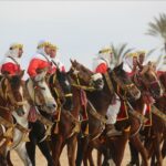 Douz, au Cœur d'une Tradition Fascinante Le Festival de Douz, aussi connu sous le nom de "Festival International du Sahara", est un événement culturel emblématique de la région du Sahel en Tunisie. Organisé chaque année, ce festival est une immersion au cœur de la richesse et de la diversité culturelle du désert tunisien. Un Événement Féérique au Cœur du Désert Tradition, Musique et Arts Nomades Le Festival de Douz célèbre les traditions séculaires des tribus nomades du Sahara. Assistez à des démonstrations éblouissantes de danses traditionnelles, de chants envoûtants et d'artisanat local, offrant ainsi un aperçu authentique de la culture nomade. Compétitions Équestres Époustouflantes Les compétitions de fantasia, une démonstration équestre traditionnelle où les cavaliers exécutent des mouvements coordonnés au rythme des musiques traditionnelles, représentent l'une des attractions phares du festival. Expérience Unique et Mémorable Découverte de l'Hospitalité Tunisienne Participez à des soirées sous les étoiles, goûtez à la cuisine locale et échangez avec les habitants pour vivre une immersion totale dans la culture tunisienne. Excursions et Découvertes Profitez du festival pour explorer les environs désertiques, des dunes majestueuses aux villages berbères pittoresques, offrant une expérience inédite et des souvenirs mémorables. Préparez Votre Visite au Festival de Douz Réservations et Hébergements Planifiez votre séjour à l'avance en réservant via SudTunisie.com pour profiter d'offres avantageuses sur les hébergements et les forfaits festivaliers. Conseils Pratiques Prévoyez des vêtements adaptés au climat désertique et n'oubliez pas de vous hydrater. Le festival attire des milliers de visiteurs, assurez-vous donc d'arriver tôt pour profiter pleinement de chaque activité. Conclusion : Vivez l'Authenticité du Sahara avec le Festival de Douz Le Festival de Douz est bien plus qu'un simple événement, c'est une immersion culturelle fascinante dans le monde des nomades du désert. Avec SudTunisie.com, plongez-vous dans cette célébration unique et créez des souvenirs inoubliables au cœur du Sahara tunisien. {narrateur-article} Le Festival de Douz est une expérience culturelle à couper le souffle, une occasion unique de découvrir la richesse et la beauté du Sahara tunisien. Rejoignez SudTunisie.com pour une aventure qui vous transportera au cœur de la tradition nomade.