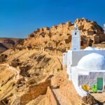 Le Sud Tunisien est une région fascinante qui offre une diversité de paysages à couper le souffle, des déserts de sable doré aux oasis verdoyantes. Pour ceux qui recherchent une aventure authentique, un circuit dans le Sud Tunisien en 2024 est une opportunité à ne pas manquer. Cet article vous propose une immersion complète dans cette région, en vous fournissant une description détaillée et un itinéraire de trois jours pour explorer le Sud Tunisien. Sud Tunisien : Une Aventure au Coeur du Désert Le Sud Tunisien est connu pour ses vastes étendues désertiques et ses paysages pittoresques. C’est une destination parfaite pour les amateurs de nature et d'aventure. Les dunes de sable de l’Erg Oriental, les montagnes du Dahar, et les oasis cachées sont autant de trésors à découvrir. Jour 1 : De Tozeur à Douz, la Porte du Désert Votre circuit commence à Tozeur, une ville célèbre pour sa palmeraie et son architecture unique en briques de terre. Une promenade à travers les ruelles étroites de la médina de Tozeur vous plongera dans l’atmosphère authentique de cette région. Après avoir exploré Tozeur, vous vous dirigerez vers Douz, connue comme la "Porte du Désert". Sur la route, faites un arrêt à Nefta, une autre oasis magnifique. Nefta est souvent appelée la "Corbeille de Nefta" en raison de sa forme et de ses nombreuses sources d'eau. Une visite de cette oasis vous permettra d’admirer ses palmiers majestueux et de déguster des dattes fraîches. À Douz, ne manquez pas le marché hebdomadaire où vous pourrez découvrir l’artisanat local et les produits traditionnels. En fin de journée, profitez d’une balade à dos de chameau dans les dunes pour admirer le coucher du soleil. Jour 2 : Ksar Ghilane et l’Oasis Perdue Le deuxième jour de votre circuit vous mènera à Ksar Ghilane, une oasis isolée au cœur du désert. Cette oasis est célèbre pour sa source d'eau chaude naturelle où vous pourrez vous baigner et vous détendre. Le contraste entre le désert aride et l'oasis verdoyante est saisissant et offre un spectacle visuel incroyable. Sur la route de Ksar Ghilane, vous aurez l'occasion de visiter des ksour, des greniers fortifiés typiques de la région. Ces structures historiques témoignent de l’ingéniosité des habitants pour stocker leurs récoltes à l’abri des pillards. Jour 3 : Matmata et les Maisons Troglodytes Votre troisième jour commence par une visite de Matmata, célèbre pour ses maisons troglodytes. Ces habitations souterraines ont été creusées dans la roche pour offrir une protection contre les températures extrêmes du désert. Une visite chez une famille locale vous permettra de découvrir ce mode de vie unique et de goûter à la cuisine traditionnelle tunisienne. Après Matmata, continuez vers Tataouine, une ville qui a donné son nom à la planète Tatooine dans Star Wars. Les alentours de Tataouine abritent des ksour impressionnants, tels que Ksar Ouled Soltane et Ksar Hadada, qui méritent une visite. Description d'une Oasis dans le Sud Tunisien Les oasis du Sud Tunisien sont de véritables havres de paix au milieu du désert. Chaque oasis possède son charme unique, avec des palmeraies luxuriantes, des sources d'eau naturelles et des villages pittoresques. L'oasis de Chebika, par exemple, est nichée au pied des montagnes et offre des vues panoramiques époustouflantes. En parcourant les sentiers de cette oasis, vous découvrirez des cascades cachées et des bassins d'eau cristalline. Les habitants des oasis vivent en harmonie avec leur environnement, cultivant des palmiers dattiers, des oliviers et des grenadiers. La production de dattes est une activité économique essentielle dans cette région, et vous pourrez déguster différentes variétés de ce fruit délicieux lors de votre visite. Sud Tunisien en Arabe : Découverte Culturelle et Linguistique Explorer le Sud Tunisien, c’est aussi s’immerger dans la culture et la langue locales. La langue arabe, parlée dans toute la Tunisie, prend des nuances particulières dans cette région. Les habitants sont connus pour leur hospitalité et leur générosité, et ils seront ravis de partager avec vous leur mode de vie et leurs traditions. Lors de vos interactions avec les locaux, vous pourrez apprendre quelques expressions arabes qui vous aideront à mieux comprendre et apprécier la culture du Sud Tunisien. N'hésitez pas à participer aux activités locales, comme la préparation du couscous ou la fabrication de tapis traditionnels, pour une expérience encore plus enrichissante. Conclusion : Un Circuit Inoubliable dans le Sud Tunisien Le Sud Tunisien est une destination qui promet des souvenirs inoubliables. Que vous soyez attiré par les paysages désertiques, les oasis verdoyantes, ou les richesses culturelles, un circuit dans cette région vous offrira une expérience unique et authentique. Préparez votre voyage pour 2024 et partez à la découverte des trésors cachés du Sud Tunisien.