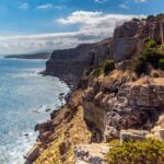 Nous proposons une excursion au Cap Bon au départ de Sousse, Hammamet, Tunis, Monastir ou Korba, afin de découvrir ce coin de paradis niché sur la côte nord-est de la Tunisie. Le Cap Bon séduit par ses paysages verdoyants, ses villes artisanales pittoresques, son littoral préservé, ses criques cachées et son ambiance relaxante. Nous aimons particulièrement ce type de découverte, car il offre un mélange parfait entre découverte culturelle, détente balnéaire et gastronomie locale, le tout dans une atmosphère authentique qui nous plonge au cœur de l’identité tunisienne. Visiter le Cap Bon : Un concentré de charme et d’authenticité Le Cap Bon, souvent considéré comme le "jardin de la Tunisie", est réputé pour ses champs d’orangers, ses vignobles, ses oliveraies et ses plantations de jasmin. Nous savons à quel point il est agréable de prendre une route côtière bordée de palmiers, d’arbres fruitiers et de petits villages colorés. Au fil des kilomètres, nous notons une transition subtile entre les rivages touristiques de Sousse, Hammamet ou Monastir, vers une ambiance plus sereine, plus rurale, où la nature reprend ses droits. Arriver depuis Tunis ou Korba facilite également l’accès, grâce à des routes confortables et bien entretenues. Ce qui nous plaît, c’est cette sensation de liberté : un itinéraire sans contrainte, où nous pouvons faire des haltes gourmandes, admirer un panorama sur la mer, ou plonger nos mains dans l’eau cristalline de plages secrètes. Les artisans et les marchés de Nabeul : La porte d’entrée du Cap Bon Nabeul constitue souvent la première étape de notre excursion. Cette ville est célèbre pour sa céramique artisanale, ses poteries et ses faïences décorées à la main. Nous aimons flâner dans les ruelles du marché, discuter avec les artisans, observer leurs gestes minutieux, et pourquoi pas, ramener un souvenir unique peint aux couleurs vives. Le vendredi, le grand marché hebdomadaire attire des visiteurs venus de toute la région : fruits, épices, bijoux en argent, tissus... Tout y est réuni pour un moment de rencontre et de partage. Prendre le temps de discuter, marchander un peu, tout en s’imprégnant des odeurs d’épices et des effluves de jasmin, nous donne déjà une première idée de l’identité singulière de ce bout de terre. Kélibia : Entre château fort, vin de Muscat et mer turquoise En poursuivant vers le nord, nous atteignons Kélibia, petite ville portuaire charmante dominée par un fort imposant. Le fort de Kélibia, perché sur une colline, offre une vue panoramique sensationnelle sur la Méditerranée. Le spectacle du bleu infini, ponctué de quelques embarcations de pêche, est un ravissement pour les yeux. Nous aimons grimper jusqu’à ce fort car il symbolise l’âme maritime de la région. Kélibia est également célèbre pour son Muscat, un vin doux et parfumé. Nous apprécions déguster quelques gorgées dans une cave locale, pour découvrir la subtilité des arômes. Puis, nous descendons sur le port pour savourer un poisson fraîchement pêché, grillé sur place, accompagné de légumes du marché. C’est un moment simple, authentique, où nous sentons battre le cœur maritime du Cap Bon. El Haouaria : L’alliance de la nature et de l’histoire En continuant vers l’extrémité nord du Cap Bon, El Haouaria nous attire par sa côte sauvage, ses grottes marines et ses faucons migrateurs. Nous apprécions de partir en randonnée sur les falaises qui surplombent la mer : le sentier, parfois escarpé, offre des panoramas à couper le souffle. Les vagues viennent s’écraser en contrebas, créant une symphonie naturelle apaisante. Les grottes d’El Haouaria, creusées par la mer, sont un témoignage de la rencontre entre la pierre et l’eau. Certains pêcheurs proposent des balades en bateau pour approcher ces cavités mystérieuses. Nous aimons cette expérience, car elle nous donne l’impression de remonter le temps, d’explorer des lieux restés sauvages et préservés. À certaines périodes de l’année, El Haouaria est réputée pour le passage des faucons. Les passionnés d’ornithologie peuvent observer le ballet majestueux de ces rapaces. Nous restons souvent sans voix devant ce spectacle, sentant la force de la nature, et l’équilibre fragile qui lie terre, air et mer. Les plages secrètes de la côte du Cap Bon Au-delà de ses villes emblématiques, le Cap Bon recèle de plages discrètes, petites criques nichées entre deux falaises, étendues de sable doré en bord de route, où nous pouvons nous arrêter à l’improviste pour un moment de détente. L’eau y est généralement limpide, d’un bleu turquoise irrésistible. Nous aimons poser nos serviettes, retirer nos chaussures, et laisser nos pieds s’enfoncer doucement dans le sable chaud. Ces plages, plus tranquilles que celles de Sousse ou Hammamet, nous offrent une intimité rare. Il n’est pas rare de n’y croiser que quelques locaux, profitant d’un après-midi ensoleillé en famille. Cela nous permet de nous fondre dans la vie quotidienne des habitants, d’échanger quelques mots, et de savourer l’instant présent. Gastronomie locale : Savourer le Cap Bon à chaque bouchée Nous ne pouvons pas parler de cette excursion sans évoquer la gastronomie. Le Cap Bon est réputé pour sa cuisine fraîche, simple, centrée sur les produits de la mer et les légumes du potager. Déguster une salade tunisienne relevée d’huile d’olive locale, un plat de poissons grillés, des crevettes parfumées à la coriandre, ou un tajine aux légumes, fait partie des plaisirs à ne pas manquer. Aux étals des marchés, les agrumes du Cap Bon, notamment les oranges de Korba, sont célèbres pour leur saveur sucrée et leur juteux incomparable. Les artisans pâtissiers proposent aussi des douceurs traditionnelles, comme les makrouds, gâteaux à base de semoule et de dattes, à déguster avec un thé à la menthe. Nous aimons ramener quelques douceurs pour prolonger le plaisir après l’excursion. Se détendre dans des hébergements de charme et lieux d’étape Que ce soit pour une journée ou un séjour plus long, nous trouvons au Cap Bon de charmants hébergements à taille humaine. Des maisons d’hôtes familiales, des petits hôtels de charme, des lodges nichés dans un cadre naturel… Nous apprécions particulièrement ces lieux, car ils conservent une atmosphère chaleureuse, loin des grandes structures impersonnelles. Il n’est pas rare de se réveiller face à la mer, de prendre un petit-déjeuner sur une terrasse fleurie, ou de s’offrir une soirée paisible loin de l’agitation urbaine. Le temps semble s’écouler plus doucement, nous permettant de savourer pleinement chaque instant. Comment organiser votre excursion au Cap Bon depuis Sousse, Hammamet, Tunis, Monastir ou Korba Partir du centre touristique de Hammamet, de la médina de Sousse, de l’élégante Tunis, du littoral ensoleillé de Monastir, ou de l’authentique Korba, est plutôt simple. Les routes sont bien aménagées, et en voiture de location, l’itinéraire peut se faire en une journée, bien que nous conseillions toujours de prendre un peu plus de temps. Une excursion depuis Tunis peut par exemple commencer tôt le matin, pour rejoindre Nabeul avant la chaleur de midi, puis filer vers Kélibia et El Haouaria, en faisant quelques arrêts photo ou baignades improvisées. Depuis Hammamet, on peut s’offrir une boucle, en remontant vers Nabeul, puis en longeant la côte vers Kélibia et en revenant par l’intérieur des terres. Transport, guides et excursions organisées Si nous préfèrons déléguer l’organisation, des agences de voyages locales proposent des circuits sur mesure. Elles connaissent parfaitement la région, les meilleurs endroits, les horaires idéaux, et peuvent même organiser des rencontres avec des artisans, des dégustations dans des caves viticoles ou des visites privées. Cette option a l’avantage de rendre l’aventure plus confortable, sans stress. Pour les amoureux du désert et d’aventures plus lointaines, il est intéressant de consulter certaines offres de circuits proposés par des spécialistes du voyage en Tunisie. Par exemple, ce lien circuits désert offre un aperçu des possibilités d’aventures plus au sud, une fois l’excursion au Cap Bon terminée. Nous aimons ce type de complément, car cela nous permet de varier les plaisirs et de découvrir des facettes très différentes du pays. Points forts et expériences uniques du Cap Bon Parmi les moments forts de cette excursion, nous gardons à l’esprit : Observer les artisans de Nabeul transformer la terre en merveilles colorées. Se promener dans un marché animé, sentir les épices, déguster quelques olives, discuter avec les marchands. Admirer le panorama depuis le fort de Kélibia, un véritable balcon sur la Méditerranée, propice à la contemplation. Déguster un Muscat de Kélibia, sucré et parfumé, parfait pour accompagner des mets locaux. Explorer les falaises d’El Haouaria, se laisser surprendre par la beauté sauvage de la côte et, si la saison s’y prête, contempler le vol des faucons. Découvrir des criques secrètes, se baigner dans une eau claire, loin de la foule. Savourer la gastronomie locale, du poisson grillé aux agrumes juteux du Cap Bon, et se laisser tenter par des pâtisseries traditionnelles. Rencontrer des habitants accueillants, échanger quelques mots, quelques sourires, et apprécier leur sens de l’hospitalité. Culture, traditions et artisanat du Cap Bon Le Cap Bon est marqué par une longue histoire. De l’Antiquité à nos jours, la presqu’île a vu passer les Phéniciens, les Romains, les Carthaginois, avant de développer sa propre identité tunisienne. Nous aimons découvrir les vestiges archéologiques, notamment ceux de Kerkouane, ancienne cité punique classée au patrimoine mondial de l’UNESCO. Ces ruines bien conservées offrent un aperçu unique de la vie dans l’Antiquité. Au-delà de l’histoire, la culture du Cap Bon se reflète dans ses traditions agricoles, ses danses folkloriques, ses fêtes religieuses ou ses foires saisonnières. Chaque événement est une invitation à la rencontre, au partage, à la compréhension mutuelle. C’est cette dimension humaine qui rend le voyage tellement riche et inspirant. Nos conseils pour profiter pleinement de l’excursion Pour une expérience idéale, il est préférable de partir tôt le matin, afin d’éviter la chaleur de midi et d’avoir le temps de flâner. Nous conseillons de porter des vêtements légers, confortables, et une paire de chaussures adaptées aux petites randonnées. Un chapeau, des lunettes de soleil et de la crème solaire ne sont pas de trop, surtout en été. Mieux vaut prévoir un sac avec une serviette de plage, un maillot de bain, et une bouteille d’eau. Cela permet de saisir les opportunités spontanées : un petit plongeon dans une crique, une pause sur une plage déserte, ou un pique-nique improvisé avec des fruits frais et du pain croustillant acheté sur un marché local. Si vous souhaitez allonger votre voyage, explorer d’autres régions plus exotiques, ou organiser un périple plus complet en Tunisie, vous pouvez solliciter un devis personnalisé en contactant ce lien : contacter pour un voyage en Tunisie. L’idée est de façonner un séjour à votre image, en mixant découverte du Cap Bon, exploration du sud saharien, et immersion dans la vie locale. Conclusion : Le Cap Bon, un joyau à portée de main Cette excursion au Cap Bon, au départ de Sousse, Hammamet, Tunis, Monastir ou Korba, est une expérience envoûtante. Nous apprécions sa simplicité, sa proximité, et la diversité de ses atouts : paysages naturels, artisanat authentique, villages pittoresques, gastronomie savoureuse et moments de partage avec les habitants. Pour nous, c’est un voyage qui révèle une autre Tunisie, plus discrète, plus secrète, mais tout aussi attachante. Le Cap Bon incarne ce parfait équilibre entre culture, nature et détente. Il suffit de laisser la route nous guider, d’ouvrir nos sens, et de profiter pleinement de chaque instant, car c’est ainsi que cette excursion restera gravée dans notre mémoire, longtemps après le retour.