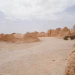 Nous invitons tous les voyageurs en quête d’évasion à découvrir le Sahara Sud Tunisien, une destination fascinante où les paysages désertiques, le patrimoine culturel et les traditions ancestrales se mêlent harmonieusement. Lors de vos vacances en Tunisie, vous aurez l’occasion de vivre des expériences uniques, mêlant confort, aventure et immersion dans des lieux encore préservés du tourisme de masse. Dans les lignes qui suivent, nous vous guidons à travers les étapes essentielles pour organiser un circuit complet et réussir une excursion inoubliable dans la région sud du pays, réputée pour ses dunes spectaculaires, ses oasis luxuriantes, ses villages pittoresques et l’accueil chaleureux de ses habitants. Découvrir le Sahara Sud Tunisien : Entre Dunes, Oasis et Villages Berbères Plonger dans le Sahara Sud Tunisien, c’est avant tout s’émerveiller devant des panoramas à couper le souffle. Les dunes immenses s’étendent à perte de vue, teintées d’or et de rose au lever et au coucher du soleil. Les oasis, quant à elles, offrent un contraste saisissant : au cœur du désert surgissent des palmeraies verdoyantes, des sources naturelles et des points d’eau cristalline, véritables havres de fraîcheur. Nous considérons ces lieux comme un véritable trésor, car ils constituent souvent un point de rencontre avec les communautés locales, les villages berbères et les petites structures familiales qui perpétuent des savoir-faire ancestraux. En flânant dans ces oasis, vous rencontrerez des tisserands, des potiers, des agriculteurs et des nomades, qui vous raconteront leurs traditions, leurs modes de vie et leur histoire. Les paysages, les parfums, les échanges humains et les saveurs locales se combinent pour créer un cocktail d’émotions mémorables, symbole d’un tourisme authentique que nous encourageons vivement. Choisir le Bon Circuit pour Explorer le Sahara : Du Classique à l’Atypique Le Sahara Sud Tunisien se prête à de nombreux circuits et excursions adaptés aux envies de chacun. Que vous soyez passionné d’archéologie, amateur d’aventure ou simplement en quête de détente, il existe forcément un itinéraire idéal pour combler vos attentes. Nous vous proposons quelques pistes pour vous aider à faire votre choix et à créer des souvenirs inoubliables. Circuit Classique : De Douz à Tozeur en Passant par les Oasis Cachées Si vous souhaitez approcher la magie du désert de manière progressive, un circuit classique reliant Douz, Kébili et Tozeur reste un incontournable. Vous commencerez sans doute par Douz, souvent surnommée la "porte du désert". Cette ville vous ouvrira les bras avec ses marchés animés, ses artisanats locaux et ses premiers paysages de dunes. Au fil du trajet, vous traverserez des zones semi-désertiques, découvrirez des oasis confidentielles et vous ferez une idée plus claire de la diversité des paysages sahariens. En chemin, ne manquez pas la palmeraie de Kébili et les lacs salés de Chott El-Jérid, dont la surface miroitante intrigue et fascine. À Tozeur, vous serez surpris par l’architecture si particulière, faite de briques décoratives, la douceur des dattes fraîches, ainsi que la diversité des excursions possibles, entre balades en calèche, randonnées dans les palmeraies, ou virées en 4x4 sur les pistes désertiques. Les circuits désert organisés, comme ceux proposés ici, vous aideront à découvrir ces merveilles avec une logistique bien rodée. Circuit Aventure : Au Cœur des Dunes de l’Extrême Sud Pour les voyageurs en quête de sensations fortes, un circuit aventure plus poussé dans l’extrême sud est parfait. Nous vous conseillons de vous enfoncer plus profondément dans le désert, vers l’immensité des dunes de l’erg oriental, où le silence est parfois si total que l’on perçoit les battements de son propre cœur. Dans cette partie plus reculée du Sahara, vous pourrez pratiquer le sandboarding, monter à dos de dromadaire pour suivre les pistes nomades, ou opter pour une sortie en quad, histoire de mêler adrénaline et émerveillement. C’est également l’occasion de passer une nuit sous la tente, dans un bivouac confortable, encadré par des guides locaux. Au crépuscule, le ciel étoilé du désert, totalement dépourvu de pollution lumineuse, offre un spectacle incomparable. Les constellations se dessinent avec une netteté déconcertante, et observer la voie lactée devient un moment de pure magie. Loin de toute agitation, vous goûterez à la solitude du désert, pour un séjour qui marquera durablement votre mémoire. Circuit Culturel : Plonger dans les Traditions du Sud Tunisien Le Sahara Sud Tunisien ne se résume pas à ses paysages : sa richesse culturelle est tout aussi fascinante. Pour un circuit culturel, nous vous recommandons de visiter des villages authentiques, comme ceux de la région montagneuse de Matmata, célèbre pour ses habitations troglodytes et son atmosphère hors du temps. Dans ces villages, les rencontres avec les habitants permettent de comprendre leurs coutumes, leur cuisine, leurs savoir-faire artisanaux. Plus au nord, dans la région, on peut également découvrir des ksour, anciennes greniers fortifiés, témoignages d’une vie passée tournée vers le troc, la gestion de l’eau et l’élevage. Certains ksour sont aujourd’hui convertis en petites pensions familiales, idéales pour passer une nuit originale et découvrir de près l’architecture traditionnelle, la musique locale et les fêtes saisonnières. Ce circuit culturel est un moyen de donner du sens à son voyage, de comprendre l’histoire, l’identité et la diversité de la Tunisie méridionale. Circuit Luxe : Confort Haut de Gamme et Expériences Exclusives Pour ceux qui n’imaginent pas voyager sans un certain confort, un circuit luxe dans le Sahara Sud Tunisien est tout à fait envisageable. Certains prestataires proposent des campements haut de gamme, avec des tentes spacieuses, équipées de literie de qualité, de sanitaires privés et d’espaces de détente. Vous pourrez déguster des mets raffinés, profiter de massages traditionnels et de soirées féeriques autour d’un feu de camp. Ce type de circuit, plus onéreux, offre une expérience unique, combinant l’authenticité du désert avec des prestations dignes des meilleurs hôtels. Cela permet de découvrir la région sans renoncer au confort, et de vivre des moments exclusifs, comme un dîner privé sous les étoiles, une excursion en montgolfière au-dessus des dunes, ou une découverte personnalisée des sites archéologiques, accompagné par des guides spécialisés. Moments Inoubliables : Ce Qu’il Faut Absolument Vivre dans le Sahara Sud Tunisien Que vous ayez opté pour un circuit classique, aventureux, culturel ou luxueux, certaines expériences sont tout simplement incontournables dans le Sahara Sud Tunisien. Nous en avons sélectionné quelques-unes pour vous inspirer. Admirer le Lever du Soleil sur les Dunes Un des plus beaux moments à vivre dans le désert est sans doute le lever du soleil. Partir avant l’aube, gravir une dune à la frontale et s’installer confortablement pour assister à la naissance du jour reste une expérience saisissante. Les couleurs pastel, le silence apaisant, la brise fraîche et la lumière qui gagne peu à peu en intensité forment un tableau magnifique. Une façon de ressentir la puissance de la nature et de comprendre le lien profond qui unit l’homme et ce grand espace. Déguster la Cuisine Locale au Cœur du Désert Goûter la cuisine locale au milieu du désert est également un plaisir rare. Les dattes fraîches, les pains cuits dans le sable, le thé à la menthe fumant, les tagines épicés et les spécialités berbères sont un régal pour les papilles. Nous vous conseillons de partager un repas autour d’un feu, entourés de guides et d’hôtes locaux, pour profiter d’un moment de convivialité et de partage, loin du tumulte des villes. Explorer les Sites Archéologiques et Historiques Le Sahara Sud Tunisien est aussi marqué par l’histoire. Certains circuits incluent la visite de sites archéologiques, de forteresses anciennes ou de villages abandonnés qui témoignent d’époques révolues. Parcourir ces lieux chargés de mémoire, où le temps semble s’être arrêté, est une expérience émouvante. Vous pourrez observer les vestiges d’anciennes civilisations, comprendre leur mode de vie, et réaliser à quel point le désert a façonné les hommes et leurs activités au fil des siècles. Rencontrer les Artisans et Marchands Locaux S’intéresser à la vie quotidienne des habitants du Sahara Sud Tunisien, c’est aussi partir à la rencontre des artisans et des marchands locaux. Dans les marchés, les souks et les ateliers, vous découvrirez des objets traditionnels, du tissage de tapis à la poterie, en passant par la sculpture sur bois ou la confection de bijoux. Ces rencontres sont souvent marquées par la gentillesse et l’hospitalité des habitants, fiers de faire découvrir leurs créations. Vous pourrez ainsi rapporter chez vous des souvenirs uniques, chargés d’histoire, qui rappelleront longtemps les moments passés dans le désert. Conseils Pratiques pour Préparer son Séjour dans le Sahara Sud Tunisien Pour profiter pleinement de votre voyage dans le Sahara Sud Tunisien, il est important de prendre quelques précautions et de bien organiser votre séjour. Nous vous suggérons d’opter pour des prestataires reconnus, qui maîtrisent parfaitement la logistique et la sécurité dans le désert, et qui sauront adapter le programme selon vos envies, votre niveau d’expérience et les conditions climatiques du moment. Prévoyez des vêtements adaptés, légers et couvrants pour vous protéger du soleil, une bonne paire de chaussures, un chapeau, des lunettes de soleil et une crème solaire efficace. Le contraste thermique entre le jour et la nuit peut être important, donc emportez également des vêtements plus chauds pour la soirée. Une gourde réutilisable est pratique pour se réhydrater tout au long de la journée. N’hésitez pas à réserver à l’avance, surtout si vous avez un circuit précis en tête. Les organisateurs, guides et hébergeurs pourront ainsi tout préparer dans les meilleures conditions. Pour obtenir plus d’informations ou pour un devis personnalisé, contactez directement les prestataires via ce lien. Aller Plus Loin : Relier le Sahara Sud Tunisien à d’Autres Régions de la Tunisie Une des forces de la Tunisie réside dans sa diversité. Après avoir découvert le Sahara Sud Tunisien, il est tout à fait possible de prolonger le voyage vers d’autres régions, afin de saisir toute la richesse culturelle et naturelle du pays. Nous vous conseillons de relier votre séjour saharien à une escapade sur la côte, par exemple à Djerba, pour profiter des plages, des villages de pêcheurs, de la gastronomie maritime et des sports nautiques. Vous pouvez aussi opter pour un itinéraire combiné incluant une visite de la capitale, Tunis, avec ses souks, sa médina classée au patrimoine mondial de l’UNESCO et ses musées richement dotés. Les sites antiques, tels que Carthage, Dougga ou Sbeitla, ne sont pas en reste et vous offriront un aperçu de l’héritage romain et punique du pays. Ainsi, votre séjour ne se limitera pas à la découverte du désert, mais deviendra un véritable panorama de la Tunisie dans toute sa diversité. Conclusion : Une Expérience Authentique au Cœur du Sahara Sud Tunisien Le Sahara Sud Tunisien se présente comme une destination incontournable pour celles et ceux qui recherchent une expérience authentique, mêlant paysages envoûtants, traditions ancestrales et rencontres sincères. En choisissant le bon circuit, en optant pour des excursions adaptées à vos envies et en prenant le temps de découvrir la culture locale, vous vivrez des moments mémorables, qui resteront gravés dans votre esprit longtemps après votre retour. Chaleur humaine, hospitalité, beauté sauvage et sérénité font du sud de la Tunisie un lieu où il fait bon voyager, se ressourcer, apprendre et admirer les merveilles que la nature et l’histoire ont façonnées au fil des millénaires. Pour préparer votre escapade, réservez vos circuits désert via ce site et n’hésitez pas à demander un devis personnalisé sur ce lien. Vous pourrez ainsi bénéficier de l’expertise de passionnés du Sahara, qui vous accompagneront pas à pas dans la réalisation de votre rêve d’aventure tunisienne, surclassant sans aucun doute toute autre expérience touristique comparable. Le Sahara Sud Tunisien vous attend, prêt à dévoiler ses secrets et à vous offrir une immersion totale, riche en sensations et en découvertes, dans l’un des plus beaux déserts du monde.