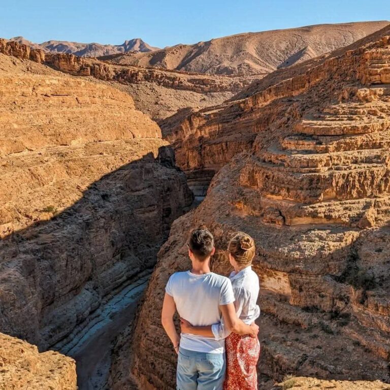 Vivre le Sahara tunisien n’a rien d’un simple déplacement d’un point A vers un point B. C’est sentir la lumière se poser sur les dunes d’or, écouter le silence des oasis au petit matin, partager le thé à la menthe avec des hôtes dont l’hospitalité est un art. Nous concevons des circuits sur mesure dans le Sud tunisien qui mêlent randonnée dans le désert, découvertes culturelles et confort maîtrisé. Qu’il s’agisse d’une échappée de 3 jours ou d’une aventure d’une semaine, chaque étape est pensée pour vous offrir un contact vrai avec les paysages, les traditions et les saveurs du pays. Circuit & randonnée en Tunisie : notre promesse d’authenticité et de confort Nous croyons qu’un circuit Sahara réussi est un subtil équilibre : suffisamment d’aventure pour ressentir l’immensité, suffisamment de confort pour savourer chaque moment. Concrètement, cela signifie des itinéraires fluides, des guides locaux passionnés, des campements sahariens choisis pour la qualité de l’accueil, une logistique sûre (4x4 récents, chauffeurs expérimentés), et des expériences immersives (méharées, bivouacs, veillées sous les étoiles). Pour visionner nos propositions et vous inspirer, découvrez nos circuits désert en Tunisie. Vous y trouverez des itinéraires détaillés, des durées flexibles et des extensions thématiques (photographie, bien-être, patrimoine, gastronomie). Itinéraires phares du Sud tunisien : de Tozeur à Ksar Ghilane en passant par Douz et Tataouine 4 jours d’émerveillement : Tozeur – Douz – Ksar Ghilane – Matmata Jour 1 – Tozeur & oasis de montagne : arrivée à Tozeur, balade dans la médina aux façades en briques ocre. L’après-midi, cap vers Chébika et Tamerza, où les cascades et palmeraies contrastent avec les reliefs minéraux. Coucher de soleil à Ong Jmel, décor cinématographique au milieu du chott scintillant. Jour 2 – Douz, la porte du désert : route vers Douz, marché traditionnel, rencontre avec les artisans. Randonnée à dos de dromadaire (méharée) pour sentir le rythme du désert, ou balade en quad pour les amateurs de sensations. Jour 3 – Ksar Ghilane & bain thermal : une oasis saharienne connue pour sa source d’eau chaude en plein désert. Installation en campement. Fin d’après-midi libre entre bain, marche sur les ergs et observation des étoiles au-dessus des tentes berbères. Jour 4 – Matmata & troglodytes : découverte des maisons troglodytiques, creusées dans la roche pour conserver la fraîcheur. Déjeuner traditionnel chez l’habitant, puis transfert retour (aéroport ou côte). Points forts : variété de paysages, premiers pas dans le désert, confort des étapes, coup de cœur pour le bain thermal de Ksar Ghilane et la belle lumière de Tozeur. 6 jours d’immersion : Douz – Tembaine – Ksar Ghilane – Tataouine – Matmata Jour 1 – Dunes de Douz : accueil, prise en main du 4x4, balade au crépuscule sur les dunes. Jour 2 – Tembaine : piste vers Tembaine, plateau isolé entouré d’ergs majestueux. Bivouac sous un ciel incroyablement pur, dîner au feu de bois. Jour 3 – Tembaine → Ksar Ghilane : marche matinale (2–3 h) pour cueillir le lever du soleil, puis route vers Ksar Ghilane et détente à la source chaude. Jour 4 – Tataouine & ksour : découverte des ksour berbères (greniers fortifiés) – Ksar Ouled Soltane, Ksar Hadada –, immersion dans l’ingéniosité architecturale du sud. Jour 5 – Chenini & Douiret : villages perchés, ruelles de pierre, panoramas qui racontent des siècles d’histoire. Jour 6 – Matmata : halte troglodyte, déjeuner de cuisine bédouine (couscous, méchoui, pain tabouna), puis transfert retour. Points forts : nuit en bivouac, marche nomade encadrée, diversité culturelle (Berbères, ksour), photogénie des reliefs et des villages perchés. 8 jours d’aventure complète : Tozeur – Douz – Grand Erg – Ksar Ghilane – Tataouine – Djerba/Monastir Jours 1–2 – Tozeur & oasis : découverte des oasis de montagne (Chébika, Tamerza, Midès), coucher de soleil à Ong Jmel. Jours 3–4 – Douz & Grand Erg Oriental : 4x4 et marche d’erg en erg, initiation à la navigation saharienne (lignes de crête, repères), veillées nomades. Jour 5 – Ksar Ghilane : pause bien-être, balade à dos de dromadaire au pied d’un ancien fort, campement confortable. Jour 6 – Tataouine : itinéraire des ksour, déjeuner dans une coopérative locale, contes et musiques du sud. Jour 7 – Matmata : exploration troglodyte, ateliers (pain, poterie, tissage) selon saison. Jour 8 – Djerba ou Monastir : fin de circuit au bord de la mer pour prolonger le séjour. Points forts : progression douce mais complète, mélange dunes–oasis–villages remarquablement équilibré, rencontres et ateliers. Expériences sahariennes incontournables : vivre le désert avec tous les sens Méharée au rythme du dromadaire : avancer lentement, respirer, écouter le sable crisser sous la patte du dromadaire ; une immersion parfaite pour ressentir le temps saharien. Randonnée sur les crêtes d’erg : marche guidée, 2 à 5 km selon votre forme ; on apprend à lire la dune, à choisir le bon appui, à repérer la faune discrète du désert. Bivouac & ciel étoilé : dîner au feu de bois, nattes et tapis, contes nomades, observation de la Voie lactée loin de toute pollution lumineuse. Bain thermal à Ksar Ghilane : un bassin naturel qui surprend au milieu des dunes ; la pause bien-être préférée des voyageurs. Quad & 4x4 sur piste : pour ceux qui aiment l’adrénaline maîtrisée, pistes et lignes de dunes avec accompagnement pro. Rencontres & hospitalité : thé partagé, initiation au pain tabouna, découverte des plantes du désert, du henna et des gestes quotidiens. Quand partir dans le désert tunisien ? Saisons, températures et lumière Le Sud tunisien se découvre idéalement d’octobre à avril : journées douces, nuits fraîches, lumière cristalline. Automne (oct.–nov.) : températures parfaites pour randonner, dunes sculptées par les premiers vents. Hiver (déc.–févr.) : ciels profonds, nuits étoilées incomparables ; prévoir une bonne polaire pour les soirées. Printemps (mars–avril) : palmeraies qui renaissent, contrastes saisissants entre oasis vertes et ergs dorés. L’été reste possible en formule confort avec activités tôt le matin et en fin d’après-midi, mais l’intensité de la chaleur le réserve à des voyageurs avertis. Hébergements & campements : du bivouac nomade au charme intimiste Nous combinons selon vos envies : Campements sahariens aménagés : tentes confortables, literie, douches ; ambiance conviviale, repas typiques. Bivouac nomade : minimaliste et magique ; une voie lactée pour plafond, le murmure du vent pour berceuse. Maisons d’hôtes & hôtels de charme (Tozeur, Matmata, Tataouine) : caractère local, petites capacités, accueil personnalisé. Chaque adresse est sélectionnée pour la qualité des services, la propreté, le respect des lieux et l’empreinte culturelle. Logistique, sécurité & encadrement : voyager serein dans l’immensité Guides locaux diplômés : experts des pistes, de la météo, de l’orientation et de la culture du désert. Véhicules 4x4 récents et chauffeurs aguerris aux terrains sableux ; pression des pneus adaptée, équipements de secours, radios et eau embarquée. Rituels de sécurité : briefing quotidien, gestion de l’hydratation, ajustement de l’itinéraire si le vent se lève. Assistance : coordination 24/7 en coulisses, relais oasis et points d’approvisionnement identifiés. Voyager dans le désert de Tunisie avec nous, c’est choisir une aventure responsable où la prudence n’empêche jamais l’émotion. Gastronomie du Sud : du pain tabouna au méchoui La cuisine saharienne est chaleureuse et généreuse : Couscous de semoule fine, légumes du marché, légumineuses parfumées au carvi et à la coriandre. Méchoui tendre, saisi doucement ; ojja (œufs et tomates), chakchouka, brik croustillant. Dattes de Tozeur, miel, figues sèches, pistaches, amandes. Thé à la menthe, pain cuit sur les braises, huile d’olive forgée par le soleil. Nous composons des menus adaptés aux régimes : végétarien, sans gluten, allergies – dites-nous tout en amont. Conseils pratiques & checklist du parfait voyageur du Sahara Vêtements : pantalons légers, chemises manches longues, coupe-vent pour le soir, polaire (hiver), foulard/cheich. Chaussures : baskets à tige basse ou chaussures de randonnée souples. Soleil : crème SPF 50+, lunettes UV, casquette/chapeau. Hydratation & snacks : gourde isotherme, fruits secs, dattes, barres céréales. Équipement utile : lampe frontale, batterie externe, appareil photo, petit sac étanche pour le sable. Étiquette saharienne : pas de traces, respect des palmeraies, économie de l’eau, attention aux plantes et aux animaux. Tarifs, inclusions & personnalisation : un voyage à votre mesure Nos circuits désert incluent généralement : Transferts et transport en 4x4 privé climatisé. Hébergement (campements, maisons d’hôtes, bivouacs selon programme). Pension complète durant la partie saharienne. Guides locaux, activités prévues (méharée, randonnée), équipements collectifs de bivouac. Assurance responsabilité civile et assistance locale. En option : quad, ateliers (cuisine, poterie), nuit supplémentaire à Djerba/Tozeur, photographe, célébrations (anniversaires, demandes en mariage dans les dunes). Chaque itinéraire est personnalisable : rythme, niveau de marche, choix d’hébergements, thématiques (familles, photographes, voyage de noces, team-building). Pourquoi choisir sudtunisie.com ? Avis, éthique & expertise locale Ancrage local : notre réseau dans les oasis, les villages et les campements nous permet d’ouvrir des portes, d’éviter la foule et de privilégier l’authenticité. Qualité éprouvée : des années de terrain, des parcours testés hors saison pour garantir des expériences stables et des alternatives en cas de vent de sable. Tourisme responsable : rémunération juste des équipes, circuits à faible impact, sensibilisation à l’environnement saharien. Satisfaction mesurée : les retours publiés par nos voyageurs parlent d’eux-mêmes – vous pouvez lire les avis et partager le vôtre ici : Sud Tunisie – Avis TripAdvisor. Réserver votre circuit Sahara en toute simplicité Prêt à tracer votre dernière empreinte sur la crête d’une dune au soleil couchant ? Deux pas suffisent : Parcourir nos circuits désert en Tunisie pour choisir l’ossature qui vous ressemble. Nous confier vos dates, votre budget et vos envies via la demande de devis : nous revenons avec une proposition personnalisée (rythme, activités, hébergements), ajustée jusqu’à l’accord parfait. FAQ express – Circuit, randonnée & excursion dans le désert de Tunisie Combien de jours pour “sentir” le Sahara ? Dès 3–4 jours, on goûte le désert. À 6–8 jours, on entre dans le rythme nomade, avec bivouac et randonnées plus longues. Faut-il être sportif ? Non. Nos randonnées sont adaptées (1 à 3 h), avec des variantes plus longues pour les marcheurs réguliers. Les activités (méharée, 4x4) diversifient l’effort. Et si le vent se lève ? Nos guides ajustent l’itinéraire : déplacement vers des zones plus abritées, réorganisation du timing. La sécurité et le confort priment. Dormir en bivouac, c’est pour moi ? Si vous aimez les ciels étoilés et les ambiances minimalistes, oui ! Sinon, optez pour un campement aménagé : confort supérieur, douche chaude, literie. Peut-on voyager en famille ? Bien sûr. Nous concevons des circuits famille avec durées de marche courtes, ateliers ludiques (pain, contes), horaires souples. Qu’emporter absolument ? Protection solaire (SPF 50+), gourde, foulard/cheich, chaussures souples, lampe frontale, veste pour les soirées. Quel aéroport privilégier ? Tozeur pour rayonner sur les oasis et Douz ; Djerba pour combiner mer et désert ; Monastir/Tunis selon vos vols et nos transferts. Un mot de conclusion : cueillir la lumière du désert Le Sahara tunisien ne se traverse pas, il se vit. Une montée de dune qui essouffle un peu, le thé brûlant qu’on savoure comme un rituel, une nuit immobile à compter les étoiles… En choisissant un circuit et randonnée en Tunisie avec nous, vous faites le pari d’une aventure authentique, dessinée sur mesure, encadrée par des experts locaux et jalonnée d’instants à haute valeur humaine. Les dunes passent, les souvenirs restent – et ils vous appellent déjà à revenir. Parcourez nos circuits désert en Tunisie, puis lancez la demande de devis personnalisée. Le reste ? Laissez-nous orchestrer vos pas : du premier coucher de soleil à Douz à la dernière poignée de main sous les palmiers de Tozeur, nous sommes là, discrètement, pour que la magie opère.