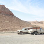 Vivre une nuit sous tente au cœur du Sahara, c’est goûter à la pureté des grands espaces, au ciel constellé et au silence qui apaise. Nous proposons un circuit 2 jours / 1 nuit souple, immersif et intensément dépaysant, avec prise en charge à l’adresse de votre choix (hôtel, aéroport, résidence, gare routière). Selon vos horaires, nous ajustons les étapes afin que vous profitiez pleinement des dunes, des oasis et des rencontres locales, sans stress ni trajets inutiles. Pour comparer les variantes, les extensions et les points forts de chaque parcours, parcourez nos circuits désert en Tunisie . Pourquoi choisir un circuit Sahara 2 jours / 1 nuit sous tente ? Le format 2j/1n concentre l’essentiel du Sahara : un soleil couchant qui incendie les dunes, une nuit sous les étoiles, un lever du jour qui dévoile des reliefs insoupçonnés, et une immersion douce dans la culture nomade. Nous avons conçu cet itinéraire pour celles et ceux qui veulent tout ressentir en peu de temps — l’aventure, l’authenticité, la sécurité — sans courir et sans renoncer au confort. Points-clés : Départ garanti depuis l’adresse de votre choix, à Tozeur, Douz, Djerba, Gabès, ou toute autre ville convenue. 4×4 climatisés conduits par des chauffeurs expérimentés, guides francophones passionnés. Bivouac sous tente : ambiance feu de camp, ciel profond, cuisine locale. Itinéraires modulables selon la saison, la météo et vos envies (balade à dos de dromadaire, randonnée, quad/buggy en option). Logistique fluide (transferts optimisés, bagages, horaires souples) grâce à notre navette aéroport . Itinéraire détaillé – Jour par jour (exemple modulable) Chaque groupe est unique : nous adaptons l’ordre des étapes, la durée des haltes et la localisation du bivouac pour que votre rythme guide le voyage. Voici un exemple d’itinéraire au départ de Tozeur (variante au départ de Djerba/Douz décrite plus bas). Jour 1 – Des palmeraies aux dunes : cap sur le campement saharien Prise en charge à l’adresse de votre choix (hôtel/aéroport). Accueil, présentation du guide, briefing sécurité et départ en 4×4 vers le lac salé. Chott El Jerid : traversée de l’immense sebkha, ses miroirs de sel et ses mirages. Arrêts photo pour saisir les pastel du ciel et les lignes blanches à perte de vue. Pause à Douz, la “porte du désert” : dégustation de dattes, réglages du matériel de bivouac. Piste saharienne : entrée progressive dans l’erg. Écoutez le 4×4 changer de rythme, observez les cordons de dunes, respirez. Balade à dos de dromadaire (option, 1–2 h) au coucher du soleil : un pas tranquille, un horizon qui s’embrase. Installation au campement : tentes traditionnelles (option confort disponible), matelas épais/linge propre. Dîner au feu de bois (couscous, tajine, salades du jour) et thé à la menthe. Veillée : contes, ciel profond, repérage des constellations à l’œil nu. Nuit sous les étoiles. Variante Djerba / Ksar Ghilane Départ de votre adresse à Djerba, route vers Médenine et ses ksour (greniers fortifiés), puis piste jusqu’à Ksar Ghilane : oasis thermale au milieu du sable. Baignade possible dans la source chaude, coucher de soleil sur les dunes, bivouac non loin dans une mer de sable doré. Jour 2 – Lever de soleil, randonnée douce et retour par les paysages lunaires Réveil au lever du jour : couleurs changeantes, dunes qui se dessinent, silence total. Petit-déjeuner saharien : pain chaud, confitures, olives, café ou thé. Randonnée douce (30–90 min) : lecture des traces d’animaux, découverte de la végétation dunaire, photo des ripple marks (dessins du vent). Option quad/buggy (selon site & disponibilité) : adrénaline contrôlée, encadrée, respect des zones sensibles. Retour : selon le point de départ, passage par Matmata/Tamezret (maisons troglodytes, belvédères), Ong Jmel près de Tozeur (décors mythiques), ou traversée du Chott El Jerid quand la lumière magnifie le sel. Dépose à l’adresse de votre choix (aéroport, hôtel, résidence). Horaires ajustés pour vos vols ou trains. Bivouac sous tente : ambiance, confort et esprit nomade Le bivouac saharien allie authenticité et sobriété confortable. Les tentes (privatives ou partagées selon l’option) sont équipées de matelas épais et de couvertures chaudes en saison fraîche. Nous proposons des camps éphémères intimistes ou des camps fixes plus équipés (sanitaires partagés/privatifs selon disponibilité). L’éclairage est doux pour laisser place au spectacle céleste ; la sécurité est assurée par notre équipe. Ce qui fait la différence : Cuisine locale préparée sur place, produits frais, recettes de tradition. Feu de camp : convivialité, échanges, musique parfois improvisée. Immersion : gestes simples, rythme du désert, histoires de piste. Services inclus & options personnalisables Inclus normalement (selon devis et point de départ) : Prise en charge à l’adresse de votre choix et transferts aller/retour en 4×4. Guide francophone et chauffeur expérimenté. 1 nuit sous tente en camp saharien (équipement selon option). Dîner, petit-déjeuner et déjeuner (Jour 2) ; eau à bord du véhicule. Assistance logistique et sécurité de base. Options fréquentes : Balade à dos de dromadaire, quad/buggy, sandboard, randonnée plus sportive (voir nos idées de randonnée en montagne & Sahara ). Campement confort (tente plus spacieuse, literie premium, sanitaires). Photographe/prise de vue drone (zones autorisées), dîner privé sous les étoiles. Extension 1 à 3 nuits : grands ergs, Grand Sud profond, villages berbères, oasis de montagne (Chebika, Tamerza, Mides). Besoin d’inspiration pour d’autres idées de journée ? Parcourez nos excursions en Tunisie . Départs & transferts – nous venons vous chercher où vous êtes Votre temps est précieux. Nous organisons des départs sur mesure avec prise en charge à l’adresse de votre choix : aéroport, hôtel, maison d’hôtes ou résidence privée. Notre navette aéroport s’occupe des arrivées tardives, des valises, des sièges enfants, et des correspondances. Exemples de points de départ : Tozeur : accès rapide au Chott El Jerid, Ong Jmel, oasis de montagne. Douz : “porte du désert”, entrée directe dans l’erg. Djerba : itinéraire via Médenine et Ksar Ghilane (source chaude au milieu des dunes). Gabès / Matmata : reliefs lunaires, maisons troglodytes, vue plongeante sur l’erg. Quand partir ? Météo, saisons et lumière Le Sahara se vit toute l’année, mais chaque saison a sa personnalité. Octobre → Avril : températures douces à fraîches la nuit. C’est la période idéale pour un bivouac confortable, des ciels très clairs et des randonnées agréables. Mai → Juin et Septembre : plus chaud en journée, soirées encore supportables. On adapte les horaires (levers matinaux, pauses à l’ombre). Juillet → Août : chaleur marquée. Possible avec départs très matinaux, siestes en milieu de journée, et campements ventilés. La lumière est un spectacle en soi : au lever et au coucher, les dunes changent de teinte minute après minute. Nos guides optimisent les haltes photo pour capter les meilleurs contrastes. Que prévoir dans votre sac ? (check-list utile) Chaussures fermées type trek léger + sandales pour le camp. Coupe-vent/polaire (soirées fraîches en automne/hiver), chèche ou casquette. Crème solaire, lunettes UV, baume à lèvres, petite trousse personnelle. Batterie externe (le réseau et l’électricité peuvent être limités en bivouac). Appareil photo/smartphone prêt pour faible luminosité (ciel étoilé !). Sac souple plutôt que valise rigide si vous prolongez dans le désert. Pour qui ? Familles, couples, amis, solo, seniors Ce circuit convient à tous les profils en bonne condition générale. Nous adaptons les rythmes et les distances (marche douce possible), proposons des menus adaptés (végétariens sur demande) et veillons aux petites attentions (sièges enfants, oreillers supplémentaires, couvertures supplémentaires en hiver). Familles : contact facile avec les dromadaires, jeu de traces dans le sable, soirée feu de camp. Couples : dîners intimistes, nuits étoilées, belvédères pour couchers de soleil. Groupes d’amis : quad/buggy, sandboard, défis photo. Voyageurs solo : immersion douce, encadrement, sécurité. Seniors : transferts confortables, pauses fréquentes, assistance à l’embarquement/débarquement. Sécurité, respect du milieu et gestes responsables Le désert est magnifique et fragile. Nos équipes sont formées aux bonnes pratiques : Respect des zones sensibles, des pistes et des habitats. Gestion des déchets et réduction des plastiques (bonbonnes d’eau + gourdes conseillées). Soutien de filières locales (achats chez les petits producteurs, artisans). Briefing sécurité clair (hydratation, soleil, marche en groupe, conduite encadrée). Votre expérience sera plus belle encore si nous la partageons avec respect. Foire aux questions (FAQ) Combien d’heures de 4×4 par jour ? Nous modulons selon vos envies. En général, 2 à 4 h étalées sur la journée, entrecoupées d’arrêts photos, pauses et activités. Peut-on modifier l’itinéraire la veille ? Oui, dans la limite des disponibilités (campements, autorisations, météo). Nous restons flexibles. Y a-t-il des sanitaires ? Selon l’option, vous dormez en camp fixe (sanitaires partagés/privés) ou en bivouac éphémère (confort simple, matériel d’appoint). Dites-nous vos préférences. Et si nous arrivons tard en avion ? Notre navette aéroport s’ajuste à vos horaires ; nous pouvons adapter l’étape du soir. Les activités sont-elles incluses ? La balade à dos de dromadaire est souvent ajoutée, le quad/buggy reste en option encadrée. D’autres idées ici : randonnée montagne & Sahara . Et s’il y a du vent ? Le vent fait partie du Sahara. Nous adaptons les horaires, privilégions des zones abritées et prévoyons des lunettes enveloppantes. Comment réserver – devis rapide et gratuit Expliquez-nous vos envies, votre adresse de départ, vos dates, vos participants et vos options (dromadaire, quad, confort, extension). Nous vous répondons rapidement avec un itinéraire sur mesure. Demande en ligne : devis gratuit – désert & Grand Sud Page circuits pour comparer : circuits désert Idées d’excursions à la journée : excursion en Tunisie Vous préférez un autre canal ou un horaire précis ? Indiquez-nous votre créneau de rappel et l’adresse exacte : nous organisons la prise en charge là où vous êtes. Avis & retours d’expérience Rien ne remplace l’avis de celles et ceux qui sont déjà partis. Parcourez les témoignages vérifiés et laissez le vôtre après votre voyage : Vos avis sur TripAdvisor – Sud Tunisie (Tozeur) . Vos retours nous aident à peaufiner les détails qui comptent : la bonne piste au bon moment, le coin d’ombre parfait, la dune au coucher de soleil qui restera votre plus beau souvenir. Prolongez l’aventure : idées de randonnées, blogs et inspirations Le désert appelle souvent… une seconde fois. Si vous avez deux ou trois jours en plus, nous concevons des boucles vers les oasis de montagne (Chebika, Tamerza, Mides), les ksour et villages berbères, ou l’erg profond. Feuilletez nos inspirations : Randonnées & trekking : randonnée montagne & Sahara Blog & carnets : blog des excursions en Tunisie Sélection de circuits : circuits désert Nous travaillons avec des équipes locales qui connaissent le désert comme leur maison. C’est ce savoir du terrain qui vous garantit des instants justes, loin des foules, au bon endroit, au bon moment. Engagement qualité : organisation millimétrée, liberté sur place Notre promesse tient en trois mots : sécurité, souplesse, sens. Sécurité : véhicules entretenus, conducteurs aguerris, suivi météo, trousse d’urgence et procédures claires. Souplesse : départ de l’adresse de votre choix, horaires ajustés, activités à la carte. Sens : respect des milieux fragiles, partenariats locaux, cuisine de saison. Le Sahara est un géant délicat : pour l’apprécier, il faut écouter ses rythmes. Nous mettons notre logistique au service de votre liberté : vous n’avez plus qu’à vivre le désert. En résumé – votre nuit saharienne en 7 temps forts Départ où vous êtes (adresse libre) et accueil personnalisé. Chott El Jerid et premiers grands horizons. Entrée dans l’erg et coucher de soleil. Bivouac sous tente, dîner au feu de camp. Nuit étoilée et lever du jour sur les dunes. Balade (dromadaire/randonnée) et options (quad/buggy). Retour souple selon vos contraintes, dépose à l’adresse de votre choix. Prêts à écrire votre propre parenthèse saharienne ? Dites-nous d’où vous partez et ce qui vous fait vibrer : nous créons le circuit 2 jours / 1 nuit qui vous ressemble. Lancez votre demande en une minute : devis gratuit ici . {stop article}