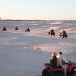 Et si, cette année, vous fêtiez Noël et le Nouvel An sous les étoiles du désert ? Imaginez-vous, loin du froid et de la routine, enveloppé par le silence doré du Sahara, autour d’un feu de camp, dans une ambiance chaleureuse et authentique. C’est exactement ce que nous proposons avec nos circuits et excursions de fin d’année dans le sud tunisien — une aventure inoubliable qui mêle découverte, émotions et dépaysement total. Un réveillon unique au cœur du désert tunisien Oubliez les soirées ordinaires, les paillettes et les restaurants bondés ! Cette année, célébrez le réveillon dans le Sahara. Sous une tente berbère confortable, autour d’un dîner typique accompagné de musique traditionnelle, la magie du désert s’invite à votre table. Nous vous emmenons vivre une expérience sensorielle et humaine unique, au milieu des dunes, sous un ciel illuminé de millions d’étoiles. Le tout dans une atmosphère conviviale, où les voyageurs partagent rires, histoires et bonne humeur. Le circuit “Fête de fin d’année Sud Tunisie” comprend : Le transport en véhicule 4x4 depuis Tozeur, Douz ou Djerba L’hébergement sous tente ou en lodge selon votre choix Les repas en demi-pension ou pension complète Le dîner du réveillon avec animation et feu de camp Un guide local francophone Une excursion dans les dunes, les oasis et les villages sahariens 👉 Découvrez nos offres sur les circuits désert . Pourquoi choisir le sud tunisien pour les fêtes de fin d’année ? Un climat doux et agréable Pendant que l’Europe grelotte, le sud tunisien offre des journées ensoleillées et des nuits fraîches mais agréables. En décembre, les températures varient entre 20°C le jour et 10°C la nuit — parfait pour profiter du désert sans souffrir de la chaleur accablante. Une ambiance authentique Passer Noël à Tozeur, Douz ou Ksar Ghilane, c’est plonger dans une culture accueillante, où l’hospitalité tunisienne prend tout son sens. Vous partagez un couscous traditionnel ou un méchoui autour du feu, accompagnés de musiciens locaux. Loin des festivités commerciales, tout est sincère, simple et chaleureux. Des paysages de rêve Les dunes de sable fin, les palmeraies verdoyantes, les montagnes ocre et les villages troglodytes offrent un décor naturel exceptionnel. Au lever du soleil, le désert s’embrase de mille nuances dorées ; au crépuscule, il s’endort dans une lumière rosée. Chaque instant est un tableau vivant. Programme type d’un circuit “Noël & Réveillon dans le Sahara” Jour 1 – Départ et immersion dans le désert Accueil à l’aéroport (avec possibilité de navette aéroport ) puis transfert vers le désert. En route, découverte des villages sahariens et des oasis mythiques. Déjeuner typique dans une auberge locale avant de rejoindre le campement. En fin d’après-midi, balade à dos de chameau sur les dunes pour admirer le coucher du soleil. À la tombée de la nuit, dîner de fête, musique, feu de camp et veillée sous les étoiles. Jour 2 – Réveil magique et exploration Lever du soleil sur les dunes — un spectacle inoubliable ! Petit déjeuner au campement puis excursion en 4x4 vers les oasis de montagne, les ksour berbères ou les sites naturels comme Ong Jmel ou les décors de Star Wars à Nefta. Déjeuner en route et retour en fin de journée. Possibilité d’ajouter une nuit supplémentaire ou une randonnée montagne Sahara pour prolonger l’expérience. Les moments forts de ce circuit festif 1. Le réveillon saharien Un dîner gastronomique revisité à la tunisienne : soupe chaude, couscous royal, agneau rôti, dattes de Tozeur, thé à la menthe… Le tout dans une ambiance magique ! Des musiciens locaux animent la soirée, parfois accompagnés de danseurs traditionnels. Et quand minuit sonne, c’est au son des tambours que vous accueillez la nouvelle année. 2. La nuit sous tente berbère Dormir dans une tente traditionnelle au milieu du Sahara, c’est une expérience à part. Le confort y est simple mais authentique, avec matelas, couvertures et lumière douce. Le silence absolu du désert favorise un sommeil paisible et profond. 3. Les levers et couchers de soleil Les couleurs du désert changent à chaque minute. Le matin, le sable s’illumine ; le soir, il s’endort sous une lumière dorée. C’est le moment idéal pour des photos sublimes et une reconnexion totale avec la nature. 4. La découverte culturelle Les guides locaux vous partagent leurs traditions, les secrets du désert, les histoires des nomades. Vous visitez des villages berbères, des marchés sahariens, des sources thermales comme Ksar Ghilane. Une aventure humaine et culturelle avant tout. Options personnalisées pour un séjour sur mesure Nous proposons plusieurs variantes selon vos envies : Circuit “Réveillon 2 jours / 1 nuit” : parfait pour une escapade rapide et intense. Circuit “Sahara & Oasis 3 jours / 2 nuits” : immersion prolongée dans le désert. Circuit “Noël berbère” : hébergement dans une maison troglodyte à Matmata, dîner traditionnel et musique locale. Extension montagne et randonnée : partez à l’aventure dans les oasis de Chebika, Tamerza ou Mides. 💡 Pour recevoir un devis gratuit et personnalisé, rendez-vous sur notre page devis voyage désert . Les incontournables du sud tunisien pendant les fêtes Tozeur Capitale du désert, Tozeur séduit par son charme, ses palmeraies et son architecture ocre. C’est le point de départ idéal pour explorer les oasis de montagne et le Chott el Jerid. Douz Surnommée “la porte du Sahara”, Douz est le cœur battant du désert tunisien. Chaque décembre, la ville accueille le Festival International du Sahara, une célébration grandiose des traditions nomades. Ksar Ghilane Cette oasis chaude et isolée offre une expérience de baignade unique dans une source thermale naturelle entourée de dunes. Matmata Connue pour ses habitations troglodytes creusées dans la roche, Matmata plonge les visiteurs dans un décor surréaliste et chaleureux. Pour explorer ces lieux, découvrez nos circuits détaillés sur Sud Tunisie - Circuits désert . Ce qui est inclus dans votre circuit de fin d’année Transport 4x4 avec chauffeur-guide francophone Hébergement (tente, lodge ou maison troglodyte selon programme) Demi-pension ou pension complète Dîner du réveillon festif Balade à dos de chameau ou en quad (option) Visites guidées des sites naturels et culturels Assistance locale et sécurité Non inclus : les boissons, les pourboires, les dépenses personnelles. Pourquoi choisir Sud Tunisie pour vos fêtes de fin d’année ? Expérience locale garantie : nos circuits sont conçus par des guides tunisiens passionnés, connaissant chaque recoin du désert. Organisation fiable et flexible : transferts, hébergements, repas… tout est soigneusement planifié. Prix transparents : aucun frais caché, et des formules personnalisables selon vos besoins. Satisfaction voyageurs : consultez nos avis sur TripAdvisor . Quelques conseils avant de partir Prévoyez des vêtements chauds pour la nuit : le désert se rafraîchit après le coucher du soleil. Apportez votre bonne humeur et votre curiosité : ici, la convivialité est reine ! Ne manquez pas votre appareil photo : chaque instant mérite d’être immortalisé. Respectez l’environnement : laissez le désert propre et paisible. Hydratez-vous bien : même en hiver, le climat est sec. Et si vous prolongiez l’aventure après le réveillon ? Pourquoi ne pas profiter de votre séjour pour explorer davantage le sud ? Nous proposons des excursions variées : Randonnée montagne Sahara : partez à la découverte des oasis suspendues. Excursion en Tunisie : découvrez les trésors cachés du pays, entre désert et mer. Blog Excursions Tunisie : retrouvez des conseils, récits et témoignages de voyageurs. Réservez dès maintenant votre réveillon saharien Les places pour les circuits de fin d’année sont limitées — les fêtes dans le désert attirent chaque année des voyageurs du monde entier. Pour garantir votre place, réservez dès maintenant ou demandez un devis gratuit sur Sud Tunisie - Devis voyage désert . Notre équipe se fera un plaisir de vous accompagner dans l’organisation d’un Noël ou Réveillon inoubliable dans le sud tunisien, entre dunes, palmeraies et ciel étoilé. Conclusion : Un Noël pas comme les autres Fêter la fin d’année dans le Sahara tunisien, c’est bien plus qu’un voyage — c’est une renaissance. Vous troquez le bruit de la ville contre le silence du désert, les lumières artificielles contre la clarté des étoiles, la routine contre l’aventure. Avec nos circuits désert Sud Tunisie, chaque moment devient une célébration de la vie, du partage et de la nature. Alors, prêt à écrire vos plus beaux souvenirs de Noël ? 👉 Découvrez toutes nos offres sur Sud Tunisie - Circuits désert 👉 Réservez votre expérience sur notre page devis gratuit . Le désert vous attend. Et cette année, c’est là que la magie de Noël prendra tout son sens.