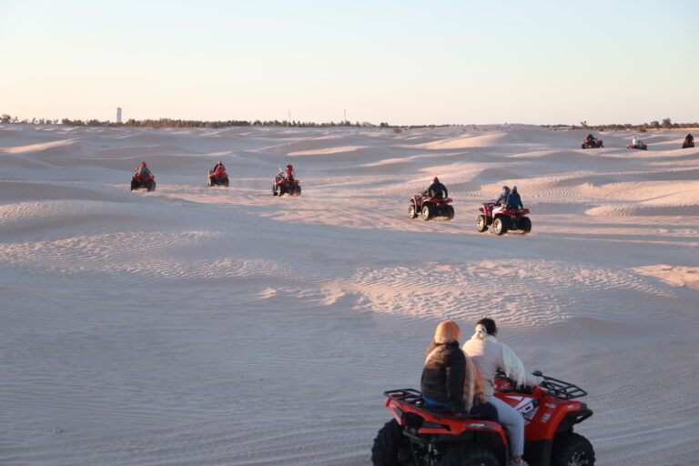 Et si, cette année, vous fêtiez Noël et le Nouvel An sous les étoiles du désert ? Imaginez-vous, loin du froid et de la routine, enveloppé par le silence doré du Sahara, autour d’un feu de camp, dans une ambiance chaleureuse et authentique. C’est exactement ce que nous proposons avec nos circuits et excursions de fin d’année dans le sud tunisien — une aventure inoubliable qui mêle découverte, émotions et dépaysement total. Un réveillon unique au cœur du désert tunisien Oubliez les soirées ordinaires, les paillettes et les restaurants bondés ! Cette année, célébrez le réveillon dans le Sahara. Sous une tente berbère confortable, autour d’un dîner typique accompagné de musique traditionnelle, la magie du désert s’invite à votre table. Nous vous emmenons vivre une expérience sensorielle et humaine unique, au milieu des dunes, sous un ciel illuminé de millions d’étoiles. Le tout dans une atmosphère conviviale, où les voyageurs partagent rires, histoires et bonne humeur. Le circuit “Fête de fin d’année Sud Tunisie” comprend : Le transport en véhicule 4x4 depuis Tozeur, Douz ou Djerba L’hébergement sous tente ou en lodge selon votre choix Les repas en demi-pension ou pension complète Le dîner du réveillon avec animation et feu de camp Un guide local francophone Une excursion dans les dunes, les oasis et les villages sahariens 👉 Découvrez nos offres sur les circuits désert . Pourquoi choisir le sud tunisien pour les fêtes de fin d’année ? Un climat doux et agréable Pendant que l’Europe grelotte, le sud tunisien offre des journées ensoleillées et des nuits fraîches mais agréables. En décembre, les températures varient entre 20°C le jour et 10°C la nuit — parfait pour profiter du désert sans souffrir de la chaleur accablante. Une ambiance authentique Passer Noël à Tozeur, Douz ou Ksar Ghilane, c’est plonger dans une culture accueillante, où l’hospitalité tunisienne prend tout son sens. Vous partagez un couscous traditionnel ou un méchoui autour du feu, accompagnés de musiciens locaux. Loin des festivités commerciales, tout est sincère, simple et chaleureux. Des paysages de rêve Les dunes de sable fin, les palmeraies verdoyantes, les montagnes ocre et les villages troglodytes offrent un décor naturel exceptionnel. Au lever du soleil, le désert s’embrase de mille nuances dorées ; au crépuscule, il s’endort dans une lumière rosée. Chaque instant est un tableau vivant. Programme type d’un circuit “Noël & Réveillon dans le Sahara” Jour 1 – Départ et immersion dans le désert Accueil à l’aéroport (avec possibilité de navette aéroport ) puis transfert vers le désert. En route, découverte des villages sahariens et des oasis mythiques. Déjeuner typique dans une auberge locale avant de rejoindre le campement. En fin d’après-midi, balade à dos de chameau sur les dunes pour admirer le coucher du soleil. À la tombée de la nuit, dîner de fête, musique, feu de camp et veillée sous les étoiles. Jour 2 – Réveil magique et exploration Lever du soleil sur les dunes — un spectacle inoubliable ! Petit déjeuner au campement puis excursion en 4x4 vers les oasis de montagne, les ksour berbères ou les sites naturels comme Ong Jmel ou les décors de Star Wars à Nefta. Déjeuner en route et retour en fin de journée. Possibilité d’ajouter une nuit supplémentaire ou une randonnée montagne Sahara pour prolonger l’expérience. Les moments forts de ce circuit festif 1. Le réveillon saharien Un dîner gastronomique revisité à la tunisienne : soupe chaude, couscous royal, agneau rôti, dattes de Tozeur, thé à la menthe… Le tout dans une ambiance magique ! Des musiciens locaux animent la soirée, parfois accompagnés de danseurs traditionnels. Et quand minuit sonne, c’est au son des tambours que vous accueillez la nouvelle année. 2. La nuit sous tente berbère Dormir dans une tente traditionnelle au milieu du Sahara, c’est une expérience à part. Le confort y est simple mais authentique, avec matelas, couvertures et lumière douce. Le silence absolu du désert favorise un sommeil paisible et profond. 3. Les levers et couchers de soleil Les couleurs du désert changent à chaque minute. Le matin, le sable s’illumine ; le soir, il s’endort sous une lumière dorée. C’est le moment idéal pour des photos sublimes et une reconnexion totale avec la nature. 4. La découverte culturelle Les guides locaux vous partagent leurs traditions, les secrets du désert, les histoires des nomades. Vous visitez des villages berbères, des marchés sahariens, des sources thermales comme Ksar Ghilane. Une aventure humaine et culturelle avant tout. Options personnalisées pour un séjour sur mesure Nous proposons plusieurs variantes selon vos envies : Circuit “Réveillon 2 jours / 1 nuit” : parfait pour une escapade rapide et intense. Circuit “Sahara & Oasis 3 jours / 2 nuits” : immersion prolongée dans le désert. Circuit “Noël berbère” : hébergement dans une maison troglodyte à Matmata, dîner traditionnel et musique locale. Extension montagne et randonnée : partez à l’aventure dans les oasis de Chebika, Tamerza ou Mides. 💡 Pour recevoir un devis gratuit et personnalisé, rendez-vous sur notre page devis voyage désert . Les incontournables du sud tunisien pendant les fêtes Tozeur Capitale du désert, Tozeur séduit par son charme, ses palmeraies et son architecture ocre. C’est le point de départ idéal pour explorer les oasis de montagne et le Chott el Jerid. Douz Surnommée “la porte du Sahara”, Douz est le cœur battant du désert tunisien. Chaque décembre, la ville accueille le Festival International du Sahara, une célébration grandiose des traditions nomades. Ksar Ghilane Cette oasis chaude et isolée offre une expérience de baignade unique dans une source thermale naturelle entourée de dunes. Matmata Connue pour ses habitations troglodytes creusées dans la roche, Matmata plonge les visiteurs dans un décor surréaliste et chaleureux. Pour explorer ces lieux, découvrez nos circuits détaillés sur Sud Tunisie - Circuits désert . Ce qui est inclus dans votre circuit de fin d’année Transport 4x4 avec chauffeur-guide francophone Hébergement (tente, lodge ou maison troglodyte selon programme) Demi-pension ou pension complète Dîner du réveillon festif Balade à dos de chameau ou en quad (option) Visites guidées des sites naturels et culturels Assistance locale et sécurité Non inclus : les boissons, les pourboires, les dépenses personnelles. Pourquoi choisir Sud Tunisie pour vos fêtes de fin d’année ? Expérience locale garantie : nos circuits sont conçus par des guides tunisiens passionnés, connaissant chaque recoin du désert. Organisation fiable et flexible : transferts, hébergements, repas… tout est soigneusement planifié. Prix transparents : aucun frais caché, et des formules personnalisables selon vos besoins. Satisfaction voyageurs : consultez nos avis sur TripAdvisor . Quelques conseils avant de partir Prévoyez des vêtements chauds pour la nuit : le désert se rafraîchit après le coucher du soleil. Apportez votre bonne humeur et votre curiosité : ici, la convivialité est reine ! Ne manquez pas votre appareil photo : chaque instant mérite d’être immortalisé. Respectez l’environnement : laissez le désert propre et paisible. Hydratez-vous bien : même en hiver, le climat est sec. Et si vous prolongiez l’aventure après le réveillon ? Pourquoi ne pas profiter de votre séjour pour explorer davantage le sud ? Nous proposons des excursions variées : Randonnée montagne Sahara : partez à la découverte des oasis suspendues. Excursion en Tunisie : découvrez les trésors cachés du pays, entre désert et mer. Blog Excursions Tunisie : retrouvez des conseils, récits et témoignages de voyageurs. Réservez dès maintenant votre réveillon saharien Les places pour les circuits de fin d’année sont limitées — les fêtes dans le désert attirent chaque année des voyageurs du monde entier. Pour garantir votre place, réservez dès maintenant ou demandez un devis gratuit sur Sud Tunisie - Devis voyage désert . Notre équipe se fera un plaisir de vous accompagner dans l’organisation d’un Noël ou Réveillon inoubliable dans le sud tunisien, entre dunes, palmeraies et ciel étoilé. Conclusion : Un Noël pas comme les autres Fêter la fin d’année dans le Sahara tunisien, c’est bien plus qu’un voyage — c’est une renaissance. Vous troquez le bruit de la ville contre le silence du désert, les lumières artificielles contre la clarté des étoiles, la routine contre l’aventure. Avec nos circuits désert Sud Tunisie, chaque moment devient une célébration de la vie, du partage et de la nature. Alors, prêt à écrire vos plus beaux souvenirs de Noël ? 👉 Découvrez toutes nos offres sur Sud Tunisie - Circuits désert 👉 Réservez votre expérience sur notre page devis gratuit . Le désert vous attend. Et cette année, c’est là que la magie de Noël prendra tout son sens.