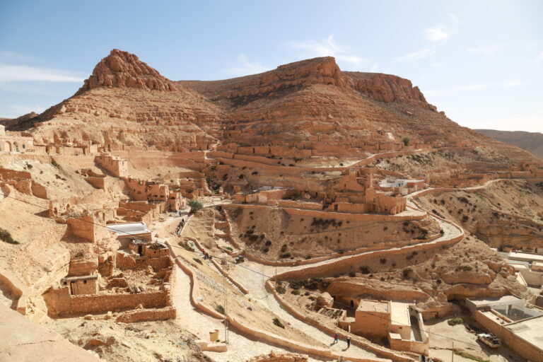 Quand on pense au Sud tunisien, on imagine tout de suite les cordons de dunes dorées, les oasis aux palmiers généreux, les villages troglodytes, les ksour perchés et ces routes mythiques qui filent vers l’infini. Nous organisons des circuits et excursions sur mesure dans le Sud de la Tunisie, avec un vrai sens du détail : transport ponctuel façon « UBER local » (navettes privées, transferts porte-à-porte), guides passionnés, hébergements authentiques et activités adaptées à votre rythme. Que vous partiez de Tunis, Hammamet, Sousse, Monastir, Sfax, Djerba, Gabès, Bizerte, Kélibia ou Korba, notre équipe coordonne chaque étape pour que vous n’ayez qu’une seule chose à faire : profiter. Les points forts d’un circuit Sahara conçu pour vous Un bon itinéraire se reconnaît à sa fluidité. Nous bâtissons nos circuits en partant de vos contraintes (dates, aéroports, niveau de confort, budget) et de vos envies (désert total, culture et archéologie, adrénaline 4×4, randonnée, slow travel…). Voici ce qui fait la différence : Transferts privés et ponctuels dès votre arrivée, avec accueil personnalisé et suivi de vol. Pour vos arrivées/départs, facilitez-vous la vie grâce à notre service de navette aéroport : voir nos navettes . Véhicules adaptés : berlines confort, vans pour familles, 4×4 climatisés pour les pistes sablonneuses. Guides locaux francophones fin connaisseurs du territoire : légendes du Chott el-Jérid, savoir-faire des nomades, flore et faune du désert, repérages cinéma (Star Wars et décors naturels). Hébergements de caractère : maisons d’hôtes, campements bédouins, hôtels de charme en oasis. Rythme maîtrisé : pas de course contre la montre, on ménage du temps pour la lumière du soir, les couchers de soleil, les pauses photo et les marchés. Expériences immersives : thé à la menthe sous la tente, dégustation de dattes Deglet Nour, atelier de cuisine du désert, balade à dos de dromadaire au crépuscule. Pour explorer nos propositions de circuits désert, consultez notre page dédiée : circuits Sahara & grands itinéraires . Si vous préférez une évasion à la journée ou 2-3 jours, misez sur une excursion en Tunisie souple et efficace : nos excursions . Les amateurs d’outdoor adoreront nos randonnées en montagne et Sahara : partir en randonnée . Et pour l’inspiration, un coup d’œil à notre blog d’excursions : lire le blog . Idées d’itinéraires : du premier contact avec les dunes à l’expédition saharienne Nous structurons les itinéraires autour de « thèmes » pour que chaque voyage ait une identité claire. Voici des exemples modulables selon la durée et votre point de départ : Tunis, Hammamet, Sousse, Monastir, Sfax, Djerba, Gabès, Bizerte, Kélibia, Korba. H2 — “Premiers pas dans le Sahara” : 3 jours entre Tozeur et Douz Jour 1 : Tozeur & Chott el-Jérid — Arrivée, transfert privé, visite de l’oasis et des quartiers en briques de sel, traversée du lac salé pour capter ces reflets surréalistes. Coucher de soleil sur une mer blanche craquelée : magique. Jour 2 : Montagnes de Tamerza & Chebika — Cascades rafraîchissantes, canyons ocres, vues panoramiques. Déjeuner dans un village de montagne et retour via Mides par une route sinueuse à couper le souffle. Jour 3 : Douz, porte du désert — Cap sur Douz, approche douce du désert : mini-trek sur les dunes, dromadaire au soleil couchant, dîner typique sous tente. Envie d’ajouter une nuit en bivouac ? Nous prévoyons un campement nomade avec feu de camp et étoiles plein ciel. Pour un devis immédiat : demander un devis gratuit . H2 — “Grand Sud et ksour” : 5 jours via Matmata & Tataouine Jour 1 : Djerba – Médenine – Tataouine — Mosquées blanches et vieux ksour (greniers collectifs). Nuit en maison d’hôtes. Jour 2 : Ksar Ouled Soltane & Chenini — Architecture berbère, panoramas infinis. Déjeuner chez l’habitant pour goûter la vraie cuisine du Sud. Jour 3 : Matmata troglodyte — Demeures creusées dans la roche, espaces frais et silencieux. Atelier photo au golden hour. Jour 4 : Ksar Ghilane — Oasis au milieu du sable : sources chaudes, quad optionnel, 4×4 jusqu’à un petit fort abandonné. Nuit en campement. Jour 5 : Douz ou Djerba — Retour en douceur, halte dattes & artisanat. H2 — “Expédition saharienne” : 7–9 jours en immersion 4×4 Tozeur – Tembaine – Ksar Ghilane – Zmela – Douz — On enchaîne piste, ergs et regs, avec navigation en 4×4, campements successifs, cuisine au feu, observation du ciel profond et réveils au silence absolu. Modules randonnée : sections à pied de 2–5 heures pour sentir le sable, apprendre à lire le relief, comprendre le vent et l’orientation. Culture vivante : halte dans des ksour habités, café sous la tente, fabrication du pain de sable. Pour une vision d’ensemble et inspirer votre propre itinéraire, parcourez nos circuits désert : voir les circuits . Excursions à la journée ou 2–3 jours : efficacité, confort, souvenirs Parfaites si vous avez peu de temps ou si vous souhaitez « goûter » au Sud avant un road trip plus long. Nous proposons des excursions au départ de Tunis, Hammamet, Sousse, Monastir, Sfax, Djerba, Gabès, Bizerte, Kélibia, Korba : Tozeur & oases de montagne : Chebika, Tamerza, Mides en une journée bien rythmée. Douz & dromadaire : initiation aux dunes, coucher de soleil, dîner nomade. Matmata troglodyte : immersion chez l’habitant, déjeuner traditionnel. Ksar Ghilane Express : baignade dans la source, quad optionnel, 4×4 vers le fort. Réservez facilement votre excursion en Tunisie : toutes nos excursions . Envie d’une randonnée plus sportive ? C’est par ici : randonnée montagne & Sahara . Transports et navettes “type UBER” : ponctualité, sécurité, sérénité Nous assurons vos transferts privés entre les grandes villes et les portes du Sahara (Tozeur, Douz, Tataouine, Matmata, Ksar Ghilane…). Notre service de navette aéroport fonctionne 7 j/7, tôt le matin et tard le soir, suivi en temps réel des arrivées et trajets : Prise en charge à l’aéroport, à votre hôtel ou à domicile. Véhicules récents : confort, climatisation, sièges enfant sur demande. Chauffeurs professionnels maîtrisant les itinéraires rapides et les haltes photo. Pour en savoir plus ou planifier votre arrivée : navettes aéroport . Quand partir et combien de jours prévoir ? Octobre → mai : la période idéale pour la lumière, des températures douces et ciel dégagé. Été : circuits adaptés (départs tôt, pauses fraîches, hébergements climatisés). Durée : 3–4 jours pour un condensé Sahara + oasis, 5–6 jours pour ksour & troglodytes, 7–9 jours pour la grande immersion en 4×4 avec bivouacs. Astuce : laissez-vous un après-midi libre en oasis pour reprendre souffle et flâner sur les marchés. Explorez nos idées et variantes : circuits désert personnalisables . Où dormir ? Campements, maisons d’hôtes, hôtels de charme Nous sélectionnons des hébergements qui racontent le territoire : Campement saharien : tentes privatives, dîner au feu de bois, ciel étoilé irréel. Maison d’hôtes : accueil familial, cuisine locale, patios ombragés. Hôtel de charme : confort moderne, piscine, spa lorsque disponible. Chaque nuit a un sens dans l’itinéraire (proximité d’un site, qualité du ciel nocturne, ambiance village, authenticité). Les retours de nos voyageurs sont consultables ici : avis clients sur Tripadvisor : lire les avis . Activités signature : vivre le désert, pas seulement le regarder Randonnée crêtes de dunes (2–4 h) : comprendre le vent, suivre les lignes, sentir l’élasticité du sable. → Nos randonnées . Dromadaire au coucher du soleil : le rythme millénaire de la caravane, parfait pour les photos. 4×4 sur erg (piloté par nos chauffeurs) : franchissements maîtrisés, sécurité et adrénaline juste ce qu’il faut. Atelier cuisine nomade : pain de sable, méchoui, couscous de l’oasis. Rencontres : café sous la tente, artisans des ksour, récolte des dattes (selon saison). Photographie : le Chott comme miroir, canyons ocre, portes bleues des villages, ciel nocturne d’une pureté rare. Envie d’un format court et efficace ? Consultez nos excursions : voir les excursions . Pour une exploration plus ample : circuits désert . Départs garantis et villes de prise en charge Nous organisons vos départs depuis : Tunis, Hammamet, Sousse, Monastir, Sfax, Djerba, Gabès, Bizerte, Kélibia, Korba. L’avantage : pas besoin de vous adapter à un point de rendez-vous imposé. Nous venons où vous êtes, y compris à l’aéroport, en hôtel ou location saisonnière. Besoin d’une prise en charge multi-villes (ex. Tunis à l’aller, Djerba au retour) ? Nous le prévoyons dès la conception de votre itinéraire. Demandez votre devis gratuit en 1 minute : formulaire de devis . Combien ça coûte ? Transparence et options Le tarif dépend de : la durée, la saison, le niveau d’hébergement, le nombre de participants, les activités (quad, dromadaire, spa) et les transferts. Pour les courts séjours, l’excursion offre un excellent rapport valeur/temps. Pour l’immersion, le circuit désert reste imbattable. Nous détaillons toujours ce qui est inclus (transports, guide, hébergements, certains repas, activités) et ce qui ne l’est pas (vols, pourboires, dépenses personnelles). Consultez nos circuits pour visualiser les combinaisons possibles : voir les circuits désert , ou contactez-nous pour un devis sur mesure : demander un devis . Family-friendly, couple ou entre amis : un Sahara pour chacun En famille : trajets fractionnés, haltes régulières, hébergements adaptés, ateliers ludiques (étoiles, pain de sable). En couple : bivouac premium, dîners privés, coucher de soleil sur l’erg, spa en oasis. Entre amis : 4×4, quad, randonnée sportive, sessions photo et couchers de soleil intenses. Solo : départs à dates flexibles, accompagnement rapproché, rythme personnalisé. Pour puiser des idées et retours d’expérience, parcourez notre blog : conseils & récits d’excursions . Conseils pratiques : préparer et réussir son circuit Tenue : couches légères, coupe-vent, chèche ou casquette, chaussures fermées. Soleil & hydratation : lunettes UV, crème, gourde réutilisable. Sacs : un petit sac de jour pour eau, appareil photo, coupe-vent. Photo : filtres pour hautes lumières au Chott, batterie de rechange. Respect : villages, souks, lieux de culte : demander avant de photographier. Saisons : nuits plus fraîches en hiver ; prévoir une polaire pour les bivouacs. Besoin d’un récap’ adapté à votre période de voyage ? Contactez-nous : devis & contact . Pourquoi nous faire confiance ? Logistique soignée : transferts “à la minute”, hébergements testés, restos choisis pour leur qualité. Ancrage local : retombées pour les communautés, circuits co-construits avec des artisans et familles. Sécurité : briefings, véhicules entretenus, itinéraires validés, alternatives en cas d’imprévu. Flexibilité : un programme reste un cadre, pas une contrainte ; on ajuste sur place selon vos envies et la lumière. Les témoignages de voyageurs sont publics : avis clients : lire les avis sur Tripadvisor . FAQ — Circuits et excursions UBER Sud Tunisie Combien de jours pour “bien voir” ? 4–5 jours suffisent pour un panorama oasis + dunes + ksour. En 7–9 jours, on s’offre l’expédition saharienne, avec bivouacs et pistes 4×4. D’où peut-on partir ? Nous organisons des départs depuis Tunis, Hammamet, Sousse, Monastir, Sfax, Djerba, Gabès, Bizerte, Kélibia, Korba. Départ aéroport ? Notre navette vous attend à la sortie. Faut-il être sportif ? Non. Nos circuits s’adaptent à votre forme. Les randonnées sont modulables : randonnée montagne & Sahara . Peut-on personnaliser à 100 % ? Oui. Durée, hébergements, activités, rythme : tout est ajustable. Voyez nos bases d’itinéraires : circuits désert . Et si je n’ai qu’une journée ? Optez pour nos excursions : idées d’excursions . Parfait pour un premier contact avec le Sahara. Comment réserver ? Remplissez le formulaire devis gratuit : devis & contact . Nous revenons vers vous rapidement avec une proposition claire. Passez à l’action : votre circuit Sahara commence ici Le Sahara tunisien n’est pas seulement un décor : c’est un rythme, une lumière, une rencontre. Pour vivre cette intensité sans contrainte, confiez-nous l’organisation de votre circuit et excursion UBER Sud Tunisie. Inspirez-vous de nos grands itinéraires : circuits désert . Explorez nos randonnées : montagnes & Sahara . Choisissez une excursion à la journée : toutes les excursions . Lisez notre blog pour préparer votre voyage : blog excursions Tunisie . Navettes aéroport et transferts privés : réserver une navette . Et surtout, obtenez votre devis gratuit en un clin d’œil : demander un devis . Nous avons hâte de vous accueillir dans le Sud tunisien, là où le désert raconte encore les plus belles histoires.