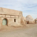 Bienvenue dans le Sud tunisien, là où les dunes chuchotent, les oasis étincellent et les soirées de réveillon se vivent au rythme des étoiles. Nous concevons des circuits privés et des excursions sur-mesure pour célébrer la fin d’année dans le Sahara en toute intimité, avec chauffeur-guide francophone, 4×4 confort, bivouacs élégants et haltes gourmandes. Notre promesse : un voyage fluide, chaleureux et mémorable, du tarmac de l’aéroport jusqu’aux crêtes dorées des dunes. Pourquoi choisir le Sud tunisien pour le réveillon ? Le désert a ce talent unique de suspendre le temps. En décembre et janvier, les températures sont douces en journée et fraîches la nuit : l’idéal pour randonner, rouler en 4×4 sur les pistes sablonneuses et partager un dîner de fête autour d’un feu de camp. Entre Tozeur, Douz, Ksar Ghilane, Matmata et Tataouine, vous traversez des décors naturels incroyablement variés : Chott el-Jérid et ses mirages, oasis de montagne (Chebika, Tamerza, Mides), villages troglodytes, ksour granitiques, sources chaudes et ergs infinis. Pour explorer nos itinéraires thématiques et comparer les durées, parcourez nos circuits désert détaillés : sudtunisie.com/voyage/circuits-desert . Nos circuits Sahara privés : 3, 5 et 8 jours pour tous les rythmes Chaque voyage est personnalisé en fonction de votre envie d’aventure, de confort et du temps disponible. Voici trois formats « best-of », modulables au jour près. 3 jours express – Le grand frisson en peu de temps Jour 1 : Tozeur – Chott el-Jérid – Douz. Accueil à l’aéroport, traversée du Chott (arrêts photo sur les mosaïques de sel), déjeuner à Douz, balade à dos de dromadaire au coucher du soleil, soirée douce sous tente berbère. Jour 2 : Douz – Ksar Ghilane. Piste vers Ksar Ghilane, baignade dans la source chaude au pied des dunes, option quad/buggy ou rando dans l’erg. Dîner festif et nuit en camp confortable (tente privative, literie chaude). Jour 3 : Matmata – Tozeur/Djerba. Visite des maisons troglodytes de Matmata, haltes panoramiques, transfert retour. Idéal pour un réveillon court mais intensément dépaysant. 5 jours signature – L’équilibre parfait Jour 1 : Tozeur & Oasis de montagne. Chebika, Tamerza, Mides : randonnées de canyon, palmeraies, cascades. Coucher de soleil sur les dunes d’Ong Jmel (décor de cinéma). Jour 2 : Chott el-Jérid – Douz. Safari photo, initiation aux pistes sahariennes en 4×4, dîner aux épices du Sud. Jour 3 : Douz – Ksar Ghilane. Dromadaires, quad, source chaude, coucher de soleil flamboyant. Soirée conviviale au camp. Jour 4 : Tataouine & les ksour. Ksar Ouled Soltane, Ksar Hadada, Chenini : architecture de greniers fortifiés, sentiers suspendus et déjeuner terroir. Jour 5 : Matmata – Djerba/Tozeur. Découverte géologique et artisanats, retour avec un carnet débordant d’images. 8 jours grand format – Immersion Sahara & patrimoine Oasis, chotts, ergs et villages : ce circuit étire le temps pour multiplier les randonnées, les ateliers (cuisine, tissage, poterie), les haltes photo, et une nuit supplémentaire en bivouac sous un ciel aux milliers d’étoiles. Vous alternez hébergements de charme en ksar/hotel troglodyte et camps premium, pour vivre un réveillon qui a de l’âme. Inspirations complètes sur : nos circuits désert . Besoin d’un devis immédiat pour caler votre voyage ? Remplissez notre formulaire en 1 minute : Demander un devis gratuit . Expériences incontournables : ce que nous aimons vous faire vivre Rencontres et terroirs. Déjeuner chez l’habitant, thé à la menthe dans une palmeraie, huile d’olive nouvelle, dattes « deglet nour » de Tozeur, semoule fine parfumée. Randonnées et panoramas. Des oasis de montagne (Chebika, Tamerza, Mides) aux crêtes douces de l’erg, nous adaptons niveaux et durées. Idées d’itinéraires à pied ici : Randonnée montagne & Sahara . Patrimoine et cinéma. Sites de Star Wars près d’Ong Jmel, ksour de Tataouine, maisons troglodytes de Matmata : de la pierre brute aux décors mythiques. Bivouac & ciel profond. Feu de camp, musique bédouine, couscous de fête, étoiles filantes : un baptême de désert à la fois simple et luxueux. Journées « explorer ». Mixez 4×4, méharée, quad/buggy et balades photo ; agrémentez d’une excursion à la carte : Excursion en Tunisie . Pour picorer des idées et lire des conseils d’initiés, jetez un œil à notre blog d’inspiration : Blog Excursions Tunisie . Réveillon dans le Sahara : une soirée de fin d’année qui a du sens Oubliez les salles bondées. Ici, la fête se fait au grand air : table dressée sous la Voie lactée, épices qui caracolent, musiciens du désert, contes et rires, compte à rebours autour du feu. À minuit, le silence du Sahara couvre les clameurs du monde : vous vous souhaitez bonne année devant un horizon infini. Le lendemain, petit-déjeuner au soleil naissant, puis balade douce pour repartir du bon pied. Nous proposons des options « Grand Réveillon » : menu gastronomique local, gâteau de fête, surprises pour les enfants, bar à thés & épices, photographe, ou encore séance d’astronomie avec laser pour repérer constellations et planètes. Logistique premium : navette aéroport, 4×4 et hébergements de caractère Votre confort est notre boussole. Dès l’atterrissage, notre équipe vous attend pour une navette aéroport sécurisée et ponctuelle : Service navette aéroport . Vos trajets s’effectuent en 4×4 climatisés récents, entretenus et assurés, conduits par des chauffeurs-guides francophones habitués aux pistes. Côté nuits : Camps dans le désert : tentes privatives, literie chaude, douches (selon catégorie), dîner aux lampions. Maisons troglodytes & ksour : charme rustique, murs de pierre, calme et fraîcheur. Hôtels de charme en oasis : piscines (selon saison), jardins, tables locales soignées. Conseils pratiques pour une fin d’année réussie Climat. Journées 15–22 °C, nuits 4–10 °C en moyenne : doudoune légère, polaire, bonnet et gants pour le soir. Tenue & matériel. Chaussures de marche, coupe-vent, lunettes de soleil UV 400, crème SPF et écharpe/cheich pour le sable. Santé & sécurité. Itinéraires validés, conduite prudente, hygiène soignée au camp. Eau en bouteille fournie. Cuisine. Couscous, méchoui, tajines, salades tièdes, dattes et pâtisseries ; options végétariennes et régimes spéciaux sur demande. Familles. Camélidés, dunes, nuits sous tente : les enfants adorent ! Nous adaptons les distances et prévoyons des pauses ludiques. Photos. Golden hours fabuleuses sur l’erg. Pensez batteries de rechange et protection sable pour l’appareil. Pour qui ? Couples, familles, groupes d’amis, entreprises Couples : bivouac cosy, dîner privé, séance photo au sunset. Familles : programme souple, ateliers (pain de sable, contes, constellations). Groupes d’amis : quads, dunes, défis photo, veillées longues. Entreprises : team-building esprit d’aventure, logistique événementielle, dîner de gala dans les dunes. Prêts à façonner votre circuit ? Décrivez-nous vos envies : Demander un devis gratuit . Nous revenons vers vous rapidement avec un itinéraire personnalisé, un budget clair et des options au choix. Exemples de journées thématiques (modulables) « Oasis & Canyons » : Chebika – Tamerza – Mides, marche au fil de l’eau, déjeuner chez l’habitant, coucher de soleil à Ong Jmel. Plus d’idées : randonnée montagne & Sahara . « Dunes & Source chaude » : Ksar Ghilane, dromadaire, baignade, fort romain, dîner à la braise. « Ksour & Mémoire » : Chenini, Ksar Ouled Soltane, Ksar Hadada ; histoires d’anciens greniers collectifs. « Troglodytes & Géologie » : Matmata et ses maisons creusées, panorama lunaire, poterie. « Excursion coup de cœur » : mix 4×4 + marche + gastronomie locale : Excursion en Tunisie . Itinéraire « Réveillon Prestige » – Proposition détaillée 5 jours Jour 1 – Arrivée & oasis Accueil aéroport (Tozeur/Djerba), navette privée vers l’hôtel, balade au coucher du soleil parmi les palmiers, dîner terroir. Jour 2 – Montagne & canyons Chebika, Tamerza, Mides : sentiers accessibles, vues plongeantes, repas en terrasse naturelle. Sunset sur les dunes d’Ong Jmel, thé à la menthe, observation du ciel. Jour 3 – Chott & Douz Route vers Chott el-Jérid, photos des miroirs de sel, déjeuner à Douz, méharée dans les dunes, atelier pain de sable, veillée conviviale. Jour 4 – Ksar Ghilane & Réveillon Baignade en source chaude, option quad, installation au camp. Dîner de réveillon aux saveurs du Sud, musiciens, vœux sous la Voie lactée. Jour 5 – Matmata & retour Visite de maisons troglodytes, céramiques et panoramas, transfert retour. Possibilité d’extension vers Tataouine (Chenini, ksour) ou Djerba. Pour d’autres variantes et retours d’expérience, consultez notre blog : Blog Excursions Tunisie . Transferts fluides et accueil 24/7 Vol tardif ? Famille avec poussette ? Groupe multi-vols ? Notre service de navette aéroport s’adapte : sièges enfant, remorques bagages, stops utiles (pharmacie, DAB, snack), suivi des vols en temps réel : Navette aéroport . Ensuite, place au confort du 4×4 : bouteilles d’eau, coussins de nuque, playlists locales, chargeurs disponibles. Avis & communautés : votre voix compte Nos voyageurs partagent leurs souvenirs, photos et conseils en toute transparence. Après votre retour, déposez un mot – c’est précieux pour les futurs explorateurs et pour notre équipe : laissez votre commentaire ici : Avis Sud Tunisie sur TripAdvisor . FAQ – Tout ce qu’on nous demande avant un réveillon dans le désert Peut-on voyager en famille en décembre ? Oui. Nous adaptons les distances, prévoyons des pauses fréquentes, des dîners plus tôt et des animations douces (contes, étoiles). Chaises bébé et sièges auto disponibles sur demande. Quelles sont les températures la nuit ? En général 4–10 °C. Les camps fournis disposent de couettes chaudes et nous recommandons bonnet + polaire. Possibilité de tentes « lodge » mieux isolées. Faut-il une condition physique particulière ? Non. Les marches sont modulables. Nous ajustons le programme selon vos envies, de la balade contemplative à la vraie randonnée : par ici . Les repas de réveillon sont-ils adaptés aux régimes spéciaux ? Bien sûr. Végétarien, sans gluten, sans lactose : dites-nous, nous personnalisons. Peut-on mixer dromadaire, quad et 4×4 ? Oui. Nos excursions sont combinables (méharée + quad + pistes) : excursions en Tunisie . Comment réserver ? Expliquez vos dates, votre aéroport d’arrivée et vos envies. Nous envoyons un projet chiffré puis vous choisissez. Formulaire direct : devis voyage désert – gratuit . Et si nous voulons prolonger à Djerba ? Facile : plages, musées, villages artisanaux, gastronomie. Nous assurons le transfert et proposons des hôtels recommandés. Passer à l’action : votre réveillon sur-mesure commence ici Nous sommes une équipe locale passionnée par le Sahara, à l’écoute, réactive et créative. Notre valeur ajoutée : des itinéraires pensés avec vous, une logistique au cordeau, des hébergements authentiques et une ambiance conviviale. Explorez nos idées de circuits désert : sudtunisie.com/voyage/circuits-desert . Inspirez-vous d’excursions à la journée : sudtunisie.com/voyage/excursion-en-tunisie . Préparez vos randonnées : sudtunisie.com/voyage/randonnee-montagne-sahara . Lisez nos récits et conseils sur le blog : sudtunisie.com/voyage/blog-excursions-tunisie . Simplifiez votre arrivée avec la navette aéroport : sudtunisie.com/services-navette-aeroport . Obtenez un devis 100 % gratuit en 1 minute : sudtunisie.com/devis-voyage-desert-sud-tunisie-vacances-pas-cher-tunisie-sahara-tunisie . En résumé : un circuit Sud Tunisie pour la fête de la fin d’année, en privé, c’est l’assurance d’un voyage qui vous ressemble, élégant sans être figé, authentique sans renoncer au confort, vivant et profondément humain. Le Sahara vous attend ; nous aussi.