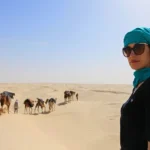 Dans le Sud tunisien, la route devient récit et chaque halte, un angle de reportage : dunes blondes, salars étincelants, villages troglodytiques, ksour fortifiés et oasis de montagne où l’eau fait front à la pierre. Nous concevons des circuits et excursions au Sud tunisien en prise en charge depuis l’adresse que vous voulez en Tunisie (Tunis, Hammamet, Sousse, Monastir, Sfax, Gabès, Djerba, Tozeur, etc.), à partir de 2 jours/1 nuit ou en itinéraires plus longs. Pour visualiser des canevas concrets et développer votre programme, parcourez nos circuits désert : nous les affinons ensuite selon votre rythme, votre saison et vos centres d’intérêt. Sud tunisien : un terrain d’enquête à ciel ouvert Le Sahara tunisien distille une variété de paysages rare à courte distance : l’horizon blanc du Chott el-Jérid, les dunes de Douz, la source chaude de Ksar Ghilane, l’architecture enterrée de Matmata, les oasis de montagne — Chebika, Tamerza, Mides — où se mêlent canyons ocres et rubans d’eau, et les ksour de Tataouine — Chenini, Douiret, Ksar Ouled Soltane —, véritables archives de pierre ouvertes au vent. À Tozeur, les façades en brique d’El-Hadef et les décors d’Ong Jmel composent une mise en scène naturelle prisée par les cinéastes. Notre couverture du terrain privilégie le format humain : peu de voyageurs par départ, une logistique souple et des rencontres documentées — thé partagé chez un gardien de ksar, dégustation de Deglet Nour chez un palmiculteur, atelier de tissage — pour inscrire chaque étape dans son contexte. Résultat : un voyage fluide, sécurisé et ancré dans le réel. Meilleure saison : choisir la bonne lumière, éviter les pics Octobre → avril : c’est la belle saison du désert. Températures clémentes le jour, fraîches la nuit ; lumières nettes, idéales pour la photo, la marche et le bivouac. Mai & septembre : intersaisons équilibrées. On avance tôt, on réserve les activités physiques à l’aube et au crépuscule, on ménage des pauses ombragées. Juin → août : chaleur marquée. Nous recommandons des formats compacts, des hébergements climatisés et des sorties aux heures basses. Sur le terrain, nous ajustons les horaires au jour le jour : la météo, la qualité de lumière et votre énergie dictent l'ordre des étapes. C’est l’assurance d’un récit bien rythmé. Circuits personnalisés : du 2 jours/1 nuit au grand reportage de 8 jours Tous nos parcours sont modulables : départ et retour depuis l’adresse que vous indiquez, intégration des vols, choix du niveau de confort (bivouac nomade, campement confort, maison d’hôtes, hôtel). Inspirez-vous sur la page circuits désert , puis demand ez les ajustements : nous éditons l’itinéraire comme un article de fond. Format 2 jours/1 nuit : le baptême du Sahara Jour 1 — Adresse de départ → Douz → erg Route vers Douz, « porte du désert ». Installation en bivouac (version poétique, dépouillée) ou camp confort (lits & sanitaires). Coucher de soleil sur la crête, dîner au feu, ciel constellé. Jour 2 — Balade chamelière → (Option) Ksar Ghilane → Retour Dromadaire au lever du jour. Selon la saison, piste vers Ksar Ghilane pour un bain en source chaude. Retour à votre adresse l’après-midi. Objectif : capter l’essentiel — dunes, nuit saharienne, aurore — sans poser trop de jours. Format 3 jours/2 nuits : Douz, Ksar Ghilane, Matmata J1 — Douz → Bivouac : boucle dunaire en 4×4, pain cuit sous la cendre, veillée. J2 — Ksar Ghilane → Tamezret → Matmata : source chaude, plateaux lunaires, habitat troglodytique. Nuit en maison d’hôtes. J3 — Villages berbères → Retour : crêtes panoramiques, déjeuner de terroir, route modulée selon vos impératifs. Format 5 jours : Tozeur, Chott, Ong Jmel, oasis, Douz J1 — Tozeur : vieille ville d’El-Hadef, palmeraie (à pied, à vélo ou en calèche). J2 — Ong Jmel → Chott el-Jérid : dunes photogéniques, décors cinéma, traversée du salar aux mirages. Nuit à Douz. J3 — Douz → Bivouac : immersion dunaire, feu, étoiles. J4 — Chebika – Tamerza – Mides : cascades, oueds, canyon ; marche douce. J5 — Tozeur : marché, dattes, musée (option), temps libre. Grand circuit 7–8 jours : dunes, ksour, troglodytes Itinéraire type : Tozeur – Douz – Ksar Ghilane – Tataouine – Chenini – Ksar Ouled Soltane – Matmata – Djerba/Tozeur/Tunis. On prend le temps : randonnées à la belle lumière, rencontres artisanes, pauses sous tamaris. Déclinable en version famille, photo ou traversée longue. Excursions à la journée : concentré d’icônes sans logistique lourde Quand le calendrier est serré, les excursions permettent de voir beaucoup en quelques heures : Oasis de montagne (Chebika – Tamerza – Mides) : marches au fil de l’eau, points de vue, villages accrochés à la roche. Ong Jmel & décors du désert : dunes ludiques près de Tozeur, spots photo spectaculaires. Matmata & Tamezret : immersion dans l’habitat troglodytique, déjeuner chakchouka/ojja. Douz au coucher du soleil : balade à dos de dromadaire, dîner méchoui. Parcourez la sélection et réservez facilement : Excursion en Tunisie . Pour des récits récents et des conseils terrain, feuilletez notre blog des excursions en Tunisie . Randonnée & trek : crêtes, oueds, dunes et nuits sous les étoiles Le Sud tunisien est un laboratoire de marche : crêtes tabulaires, canyons étroits, vallées d’oueds, ergs doux. Nous bâtissons des boucles sur mesure (familial, intermédiaire, sportif), avec ou sans chameaux de bât. Randonnée Montagne & Sahara : alternance minéral/sable, panoramas grand angle, rythme contemplatif. Bivouac nomade : tente légère, voie lactée dense, silence compact. Logistique raisonnée : véhicule d’assistance si nécessaire, points d’eau planifiés. Pour les variantes, niveaux et check-lists, explorez : Randonnée montagne – Sahara . Départs “porte à porte” : une promesse simple, des détails qui comptent Nous venons vous chercher où vous voulez en Tunisie — domicile, hôtel, maison d’hôtes, aéroport — et nous vous y reconduisons. Cette souplesse évite les « jours perdus » et améliore la qualité du temps sur site : plus de lumière utile, plus de pauses choisies, moins de transferts superflus. En amont, nous définissons avec vous : la fenêtre de départ (aube, matin, après-midi, soirée) ; la répartition des temps (visite, marche, repos) ; le niveau de confort (bivouac, camp, hébergements de charme) ; les thèmes prioritaires (photo, géologie, artisanat, gastronomie). Sécurité, confort, éthique : nos engagements de terrain Guides et chauffeurs expérimentés : lecture de piste et de météo, adaptation continue de l’itinéraire, gestion des aléas (sable, vent, chaleur). Hydratation & pauses : rappels réguliers, zones d’ombre, siestes courtes aux heures chaudes. Équipement : trousse de premiers secours, moyens de communication adaptés aux zones isolées. Respect des sites : rester sur les pistes, ne rien laisser, valoriser l’artisanat local et les hôtes qui entretiennent le territoire. Hébergements & table locale : du bivouac simple au campement confort Bivouac nomade : la nuit la plus éloquente — feu, ciel, histoires. Campement confort : lits, sanitaires, électricité ; idéal en famille. Maisons d’hôtes & hôtels : adresses de caractère à proximité des sites, pour réduire les transferts. À table, place au goût : couscous, tajines, brik, salades, pain tabouna, dattes, huile d’olive. Régimes végétariens ou sans gluten gérés sur simple information en amont. Check-list utile : voyager léger, prévoir l’essentiel Indispensables : chèche/casquette, lunettes UV, crème solaire, gourde ou poche à eau, coupe-vent léger, lampe frontale, chaussures de marche. Vêtements : multicouches (journées tempérées, nuits fraîches d’octobre à avril). Photo : batteries de rechange, filtre UV/polarisant, chiffon microfibre (sable). Bagage : privilégier le sac souple pour le chargement en 4×4. Santé : hydratation régulière, encas salés/sucrés, petite trousse personnelle. Trois enchaînements intelligents pour relier l’essentiel Tozeur → Oasis de montagne → Chott el-Jérid → Douz Un grand angle sur le Sud : eau, pierre, sel, sable. Idéal en 3–5 jours avec une nuit en bivouac. Douz → Ksar Ghilane → Tataouine (ksour) → Matmata La séquence « désert vivant » : dunes, source chaude, mémoire de pierre, habitat creusé. Parfait en 3–4 jours. Tozeur → Douz → Ksar Ghilane → Chenini → Matmata → Djerba La boucle signature en 7–8 jours : diversité maximale sans courir, fin sur la mer si vous le souhaitez. FAQ — questions que l’on nous pose avant de partir Combien de jours pour “bien” voir le Sud ? En 2 jours/1 nuit, vous vivez l’essentiel (dunes, nuit saharienne, lever du jour). En 3–5 jours, vous ajoutez oasis et Chott. En 7–8 jours, ksour et troglodytes complètent la fresque. Est-ce adapté aux enfants ? Oui. Étapes raccourcies, pauses fréquentes, campements confort, activités ludiques (dromadaire, mini-rando, découverte d’atelier). Le bivouac est-il confortable ? Deux versions : nomade (simple, poétique) ou confort (lits, sanitaires). Nous conseillons selon la saison et votre profil. Peut-on partir de n’importe où ? Oui, prise en charge depuis l’adresse que vous voulez en Tunisie. Nous calons les horaires sur vos vols ou vos impératifs. Où trouver des idées d’itinéraires complémentaires ? Parcourez nos circuits désert , nos excursions et nos articles de blog . Et pour la marche ? Nos boucles et niveaux sont détaillés ici : Randonnée montagne – Sahara . Réserver, modifier, confirmer : un devis gratuit, des options claires Un bon voyage commence par une brève prise d’informations : dates, ville ou adresse de départ, envies dominantes (photo, marche, culture, bivouac, famille), budget et niveau de confort. Nous revenons avec une proposition sur mesure, que nous peaufinons jusqu’à l’accord final. → Demander un devis gratuit – Désert Sud Tunisien → Explorer les trames : Circuits désert à développer → Voir l’offre courte et ciblée : Excursion en Tunisie → Préparer la marche : Randonnée montagne – Sahara → Piocher des retours et conseils : Blog des excursions Tunisie Après votre retour, votre regard compte : laissez un commentaire sur notre page TripAdvisor pour éclairer les futurs voyageurs et nourrir nos améliorations. Conclusion : un désert, des chemins, votre histoire Le Sud tunisien n’est pas une carte postale figée : c’est un terrain vivant qui réclame du temps, de la lumière et des choix lucides. En départ depuis l’adresse de votre choix, en deux jours/une nuit ou sur une semaine complète, nous mettons en scène un itinéraire fiable, documenté et humain. Il ne reste qu’à préciser vos priorités — dunes au crépuscule, marche en crête, ksour oubliés, troglodytes de Matmata — : nous assemblerons le reste, avec l’exigence d’un reportage bien monté et la douceur d’un voyage qui vous ressemble. Pour commencer à tracer la ligne sur le sable, ouvrez la page : https://sudtunisie.com/voyage/circuits-desert/ , puis demandez votre devis gratuit . Le reste ? C’est la lumière qui décidera.