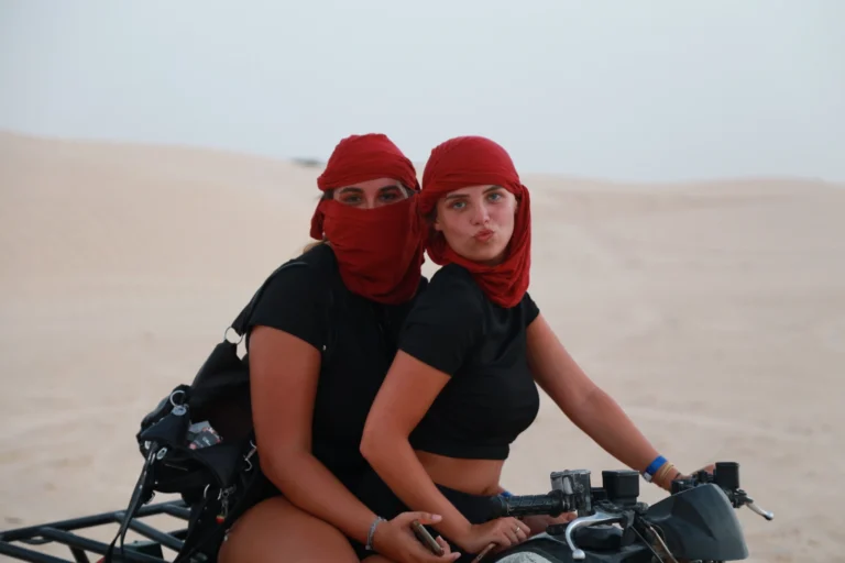 Passer la fin d’année au Sahara tunisien, c’est s’offrir une parenthèse lumineuse entre dunes dorées, oasis vivantes et ciels constellés. Nous créons des circuits privatifs et des excursions sur-mesure pour Noël et le Nouvel An : itinéraires flexibles, hôtels et campements de caractère, guides locaux passionnés, logistique fluide dès votre arrivée. Que vous rêviez d’un réveillon sous les étoiles, d’une immersion douce en famille ou d’un road trip avisé entre Tozeur, Douz, Matmata, Chenini et Ksar Ghilane, nous réglons chaque détail pour que votre séjour soit simple à vivre et inoubliable. Pour explorer nos idées d’itinéraires, parcourez nos circuits désert . Pourquoi le Sahara tunisien est idéal pour Noël & Nouvel An ? La saison de fin d’année en Tunisie conjugue météo douce, fréquentation raisonnable et lumières spectaculaires sur les reliefs. En choisissant un circuit en privé, vous profitez : d’un rythme à votre mesure : départs tôt pour les plus belles lumières, siestes ou pauses gourmandes quand vous voulez ; de trajets optimisés entre sites majeurs (Chebika, Tamerza, Mides, Chott El Jerid, Douz, Ksar Ghilane, Matmata, Chenini) pour éviter les foules ; d’hébergements vérifiés (maisons d’hôtes, lodges, campements confort) adaptés à votre budget ; d’une logistique clé en main, incluant la navette aéroport (Tozeur, Djerba ou Tunis selon vos vols) ; d’expériences authentiques : pain cuit sous le sable, thé à la menthe, ateliers d’artisanat, rencontres avec les habitants des oasis. Nous pensons le voyage comme une suite de moments forts : coucher de soleil sur une crête de dunes, bivouac confortable au milieu de nulle part, matinées dorées dans les gorges de montagne, banquet saharien pour le réveillon. Nos circuits désert de fin d’année : privatisés & 100% personnalisables Chaque voyage est construit sur-mesure : durée, confort, activités, équilibre “route / détente”. Pour vous projeter dès maintenant, découvrez la collection circuits désert ; nous y adaptons l’ambiance “fêtes de fin d’année” (menus de réveillon, moments signature, petites attentions en chambre). En complément, nos excursions en Tunisie permettent d’ajouter une journée thématique (oasis, dunes, villages troglodytiques, artisanat) à un séjour plus court. Programme type “Noël & Nouvel An au Sahara” – 6 à 8 jours en privé Un canevas efficace, modulable en 6, 7 ou 8 jours, qui couvre les incontournables sans courir. Nous personnalisons ensuite chaque journée selon vos envies (famille, couple, amis, photographie, randonnée, bien-être). Jour 1 – Arrivée & première immersion Accueil par notre équipe et transfert privé via la navette aéroport jusqu’à votre maison d’hôtes. Balade tranquille dans l’oasis ; briefing personnalisé : météo, choix des spots “golden hour”, options réveillon, souhaits culinaires. Dîner local et nuit sereine. Jour 2 – Chebika, Tamerza, Mides : les oasis de montagne Montée progressive vers les terrasses verdoyantes et canyons sculptés. Chebika pour les palmeraies, Tamerza pour ses panoramas, Mides pour sa gorge spectaculaire. Nous ajustons le timing pour éviter les heures d’affluence et profiter d’une lumière rasante parfaite. Possibilité d’une mini-randonnée (facile à modérée) à piocher dans Randonnée montagne & Sahara . Jour 3 – Chott El Jerid & Douz : portes du Sahara Au matin, traversée du Chott El Jerid, lac salé aux miroirs de lumière. Arrêts photos sur les lignes de sel, route vers Douz. Balade à dromadaire au crépuscule (en option), initiation au pain de sable, dégustations de produits dattiers. Selon vos envies, première nuit en campement : tentes privées, literie douillette, dîner sous les lanternes. Jour 4 – Mer de dunes & bivouac confort Journée hors-piste entre ergs et regs. Déjeuner en mode pique-nique gourmand, haltes “photo-spotting” sur des arêtes de dunes. Installation au camp saharien (sanitaires partagés ou privatifs selon la catégorie). Observation des étoiles après dîner : le silence, le ciel profond, le temps suspendu. Jour 5 – Ksar Ghilane & source chaude Route vers Ksar Ghilane, oasis ourlée de dunes, bain en source chaude (selon la météo), farniente sous les palmes. Boucle 4×4 possible vers un vieux fortin pour des vues à 360°. Cap ensuite sur Matmata (maisons troglodytiques) pour une rencontre avec des familles gardiennes d’un art de vivre millénaire. Jour 6 – Matmata troglodytique & Chenini (Tataouine) Visite immersive des habitations troglodytiques de Matmata (architecture vernaculaire, ingénierie climatique naturelle), puis route vers Chenini et ses ksour (greniers collectifs). Pause tisanes, atelier d’artisanat (poterie, tissage). Nuit en maison d’hôtes de charme ou retour vers Djerba. Jour 7 – Djerba & Guellala, Houmt Souk Flânerie à Guellala, village de potiers, puis Houmt Souk : ruelles, échoppes, déjeuner de poissons. Nous profitons de cette journée pour peaufiner votre soirée du 31 décembre ou du 24 décembre (selon vos dates) : table en bord de mer, ambiance musicale en ville ou retour au désert si vous préférez un réveillon intime. Jour 8 – Départ en douceur Derniers achats, plage ou dernière mini-excursion. Transfert retour soigné. Vous repartez avec notre carnet de souvenirs et vos plus belles photos. Pour varier les plaisirs, nous alternons routes scéniques, temps de repos, séances photo au lever/coucher, balades tranquilles choisies sur Randonnée montagne & Sahara , et moments conviviaux avec les habitants. Réveillon saharien : dîner sous les étoiles & ambiance chaleureuse Nous organisons sur demande un réveillon inoubliable en campement : Dîner saharien (chorba parfumée, couscous, méchoui, pain de sable, dattes Deglet Nour, douceurs) ; Musique traditionnelle ou veillée contée autour du feu (selon disponibilité et souhaits) ; Mise en scène sobriété élégante : lanternes, ciel étoilé, silence préservé ; Retrait des déchets et respect des lieux (pas de feux d’artifice dans les dunes, pour des raisons de sécurité et d’écosystème). Pour un réveillon urbain, nous suggérons des adresses chaleureuses à Djerba, Tozeur ou Tataouine, tout en privatisant les transferts grâce à la navette aéroport et à nos chauffeurs 4×4. Hébergements & campements : confort, cachet & emplacement idéal Nous sélectionnons des adresses testées : Maisons d’hôtes de charme (hospitalité, cuisine familiale, calme) ; Lodges & hôtels 3★ à 5★ selon votre standard ; Campements sahariens avec tentes privées, sanitaires soignés, douches chaudes ; Bivouacs exclusifs (sur demande) : isolation totale, équipe dédiée, protocole de sécurité. Chaque choix répond à des critères précis : propreté, literie, silence nocturne, proximité des sites pour maximiser vos heures dorées. Comparez, puis concevez votre mix idéal à partir des circuits désert . Expériences & activités à ajouter Balade à dromadaire au crépuscule : icône du Sahara, parfaite pour les familles ; Boucles 4×4 “photo-spotting” : repérage des courbes de dunes les plus graphiques ; Randonnées facile à modérées dans les oasis de montagne et sur l’erg : idées sur Randonnée montagne & Sahara ; Ateliers & rencontres : poterie à Guellala, tissage, herboristerie ; Parenthèses bien-être : bain de source chaude à Ksar Ghilane (selon la météo) ; Excursions ciblées à greffer via Excursion en Tunisie ; Inspiration & récits : blog des excursions en Tunisie . Conseils pratiques de fin d’année : météo, équipement, rythme Températures : journées douces, soirées fraîches ; emportez couches superposables, coupe-vent, chèche ou casquette. Soleil & confort : lunettes, crème solaire, baume à lèvres ; gourde réutilisable pour limiter les plastiques. Chaussures : baskets ou chaussures de marche légères (sable + sentiers). Photo : filtres UV, chiffon anti-poussière, batteries externes. Santé : petite trousse (pansements, antiseptique, antalgiques) ; assurance voyage à jour. Réservations : sur la période Noël / Nouvel An, anticipez pour sécuriser les coup de cœur (campements, chambres de charme, musiciens). Transferts & logistique : simplicité totale dès l’atterrissage Nous coordonnons vos vols et mettons en place la navette aéroport à Tozeur, Djerba ou Tunis : Accueil personnalisé, chauffeur ponctuel, eau à bord, sièges enfants si besoin ; Transferts privés entre aéroports, hôtels, oasis, campements ; Horaires ajustés pour ne rien manquer des heures dorées et revenir sereins après le réveillon. Tarifs, disponibilités & devis express Le prix dépend de la durée, du niveau d’hébergement, du nombre de voyageurs et des activités. Obtenez une estimation claire en 2 minutes via notre devis gratuit et sans engagement . Nous détaillons inclus / non inclus et proposons des options (réveillon saharien, musiciens, ateliers, extensions balnéaires ou culturelles). Avis & confiance : ce que disent nos voyageurs La satisfaction de nos hôtes guide nos choix. Lisez des retours transparents et des expériences vécues sur Tripadvisor : Sud Tunisie – Tozeur . Ces témoignages reflètent notre exigence de qualité et notre sens du détail. FAQ – Fin d’année au Sahara en privé Combien de jours pour un beau panorama du Sud tunisien ? Nous recommandons 6 à 8 jours pour combiner oasis, dunes, villages, avec un rythme confortable. 4–5 jours restent possibles pour une mise en bouche. Réveillon dans le désert ou en ville ? Les deux ! Réveillon saharien (campement, dîner sous les étoiles, veillée musicale) pour la magie ; réveillon urbain (Djerba, Tozeur) pour l’animation. Nous réservons et organisons vos transferts. Fin d’année adaptée aux enfants ? Oui. Étapes courtes, temps calmes en milieu d’après-midi, activités ludiques (dromadaire, pain de sable). Nos guides s’ajustent au rythme familial. Peut-on ajouter de la marche ? Bien sûr : boucles faciles dans les oasis et sur les bords d’erg, tirées de Randonnée montagne & Sahara . Faut-il craindre le froid la nuit ? Les campements fournissent couvertures et literie adaptées ; nous suggérons une couche thermique légère pour un confort optimal. Comment réserver simplement ? Parcourez nos circuits désert , puis demandez votre devis gratuit personnalisé . Nous ajustons, vous validez. Itinéraires associés & extensions “début d’année” Grand tour des oasis & ksour : Chebika, Tamerza, Mides, Matmata, Chenini, Douiret, Ksar Ghilane – base circuits désert . Version “nature active” : plus de pas, plus de points de vue ; piochez des idées sur Randonnée montagne & Sahara . Focus artisanat & saveurs : ajoutez des excursions en Tunisie et suivez les tendances sur le blog . Séjour mixte désert & mer : terminez à Djerba pour un début d’année tout en douceur. Prêts pour un Noël ou un Nouvel An magistral sous les étoiles du Sahara ? Transformez votre fin d’année en souvenir magistral : une nuit de réveillon au milieu des dunes, un lever de soleil sur le Chott, la chaleur des oasis en hiver. Commencez par explorer nos circuits désert , puis demandez votre devis gratuit détaillé . Pour enrichir l’aventure, ajoutez une randonnée montagne & Sahara , pimentez d’une excursion ciblée et glanez des idées fraîches sur le blog des excursions en Tunisie . Nous préparons, vous savourez. Joyeuses fêtes au Sahara !