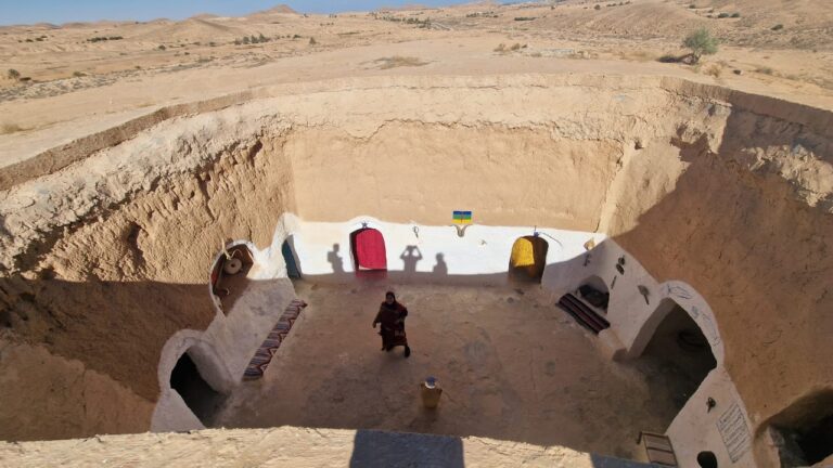 Au cœur du Sahara sud tunisien, nous proposons un circuit privé sur-mesure avec nuit sous tente pour vivre l’essence du désert : dunes dorées à l’infini, ciels constellés, silence minéral et hospitalité bédouine. Que vous rêviez d’un bivouac nomade en pleine mer de sable, d’un camp de charme confortable avec douches chaudes et cuisine traditionnelle, ou d’un mix d’oasis, ksour et villages troglodytes, notre équipe façonne un itinéraire fluide, sûr et riche en rencontres. Départs garantis depuis Douz, Tozeur, Djerba, Gabès, Matmata ou Tunis, avec 4×4 climatisés, chauffeurs-guides certifiés et assistance 24/7. Découvrez ci-dessous nos programmes phares (2 à 5 jours), des conseils d’experts pour bien préparer votre aventure, une FAQ complète et un appel à l’action pour recevoir votre proposition personnalisée. Pourquoi choisir un circuit privé dans le Sahara du sud tunisien ? Un circuit privé vous laisse le contrôle du rythme, des arrêts photo, des temps de marche et des expériences. Nous adaptons chaque journée à votre style : contemplation, randonnée douce, rencontre d’artisans, initiation à la cuisine au feu de bois, fauconnerie, balade à dromadaire ou photographie nocturne. Flexibilité totale : horaires modulables, pauses où la lumière est la plus belle, détours vers un ergs isolé si les conditions le permettent. Accès à des sites confidentiels : dunes de Tembaine/El Mida, erg oriental près de Zmela, sources chaudes de Ksar Ghilane, anciennes pistes caravanières. Confort et sécurité : 4×4 récents, radios/VHF, suivi météo, réserves d’eau et trousse d’urgence embarquées. Immersion culturelle : tentes bédouines, pain de sable, thé à la menthe, musique au guembri, légendes des pistes. Accompagnement premium : chauffeur-guide francophone/anglophone, cuisinier de bivouac quand nécessaire, matériel de campement qualité expédition. Pour une première inspiration, explorez nos idées de circuits désert ici : circuits Sahara & désert du Sud . Itinéraire type 3 jours / 2 nuits – Douz • Ksar Ghilane • Dunes de Tembaine (ou Zmela) • Matmata Jour 1 – Douz → Ksar Ghilane (oasis & source chaude) → Bivouac dans les dunes Accueil à Douz, porte du désert. Briefing sécurité et ajustement des bagages (soft bags recommandés). Piste vers Ksar Ghilane, petite oasis lovée entre palmeraie et remparts d’un ancien fort romain. Baignade possible dans la source chaude, café bédouin, balade à dromadaire (en option). En fin d’après-midi, cap sur les dunes de Tembaine ou vers Zmela selon le vent. Montage du camp au coucher du soleil : thé, pain cuit sous le sable, tajine ou méchoui selon logistique. Veillée sous la voûte céleste—initiation à la photo des étoiles si vous le souhaitez. Jour 2 – Dunes intérieures • Ergs & ergs Réveil aux premières lueurs pour un lever de soleil irréel. Après le petit déjeuner, navigation entre les cordons dunaires. Selon votre envie : marche douce (45–90 min) pour ressentir la texture du sable, jeu de pentes pour les amateurs de sandboard (en option) ou simple contemplation depuis une crête. Déjeuner au camp, sieste à l’ombre, puis piste panoramique l’après-midi. Seconde nuit sous tente : soirée contes sahariens, constellations, café touareg. Jour 3 – Désert → Matmata (maisons troglodytes) → Douz / Djerba / Gabès Décampement tardif pour profiter de la lumière douce. Route vers Matmata, rencontre avec l’architecture troglodyte sculptée dans le grès—patios circulaires, pièces fraîches creusées à même la roche, artisanat de tapis et poterie. Déjeuner chez l’habitant ou en auberge. Transfert retour (Douz, Djerba, Gabès ou Tozeur selon votre plan de vol). Fin de nos services. Points forts : dunes « carte postale », source chaude de Ksar Ghilane, double nuit saharienne pour ressentir l’alternance des lumières (aube/aurore/voûte étoilée), découverte des troglodytes de Matmata. Variante 4 jours / 3 nuits – Tozeur • Chott el-Jérid • Ong Jmel • Chebika & Tamerza • Douz • Tembaine Jour 1 – Tozeur & le Chott el-Jérid Arrivée à Tozeur, capitale des oasis. Tour des palmeraies et ruelles en brique ocre. Traversée du Chott el-Jérid, lac salé aux mirages spectaculaires (arrêt photo aux « roses de sel »). Coucher de soleil à Ong Jmel et set Star Wars (option), nuit à Tozeur ou Nefta. Jour 2 – Montagnes de l’Atlas : Chebika, Tamerza, Mides Les oasis de montagne dévoilent des canyons verdoyants : marche facile à Chebika le long du ruisseau, panorama sur le Grand Erg Oriental depuis Tamerza, corniche de Mides à la frontière algérienne. Retour vers Douz en fin d’après-midi. Dîner et nuit à Douz. Jour 3 – Douz → Tembaine (ou Zmela) Entrée dans le « dur » du désert : cap plein sud-est. Atelier de lecture de dunes, pauses photo sur les dorsales où le vent dessine des vagues parfaites. Installation du bivouac privé, soirée feu de camp, cuisine bédouine, observation du ciel profond. Jour 4 – Tembaine → Ksar Ghilane → Djerba / Gabès / Tozeur Petit-déjeuner en plein erg, puis grande diagonale vers Ksar Ghilane pour une baignade finale. Transfert retour selon vos vols. Points forts : combinaison montagnes + désert pur, variété folle de paysages, palmeraies, canyons, chotts et ergs en un seul voyage. Nuit sous tente : bivouac nomade ou camp de charme ? Nous proposons deux styles, tous deux privés : Bivouac nomade privé : tente bédouine ou igloo premium, matelas confort, couettes chaudes, tapis, table basse, lanterne, sanitaires portatifs, douche « saharienne » (eau tiède), cuisine au feu de bois. L’expérience la plus immersive et silencieuse—seul votre groupe au milieu des dunes. Camp de charme : tentes spacieuses équipées (lits, draps, électricité solaire), sanitaires communs ou privés selon catégorie, tente-restaurant, parfois douche chaude et Wi-Fi au salon. Confort supérieur, idéal pour familles avec enfants ou hiver doux. Dans les deux cas : équipe locale aux petits soins, repas généreux (salades, couscous, tajines, grillades), thé à la menthe et pain cuit sous le sable au petit matin. Logistique & sécurité : 4×4, équipe, autorisations Véhicules : 4×4 récents, climatisation, pneus désert, compresseur, plaques de désensablage, radio/VHF, GPS. Équipe : chauffeur-guide expérimenté, cuisinier de campement si bivouac, accompagnateur supplémentaire pour groupes. Sécurité : suivi d’itinéraire, check météo/vents, zones autorisées, gestion du timing pour éviter la chaleur forte. Rythme : alternance piste/sable, pauses régulières, hydratation et collation. Enfants : itinéraires doux possibles (dunes faciles, camp confort, horaire sieste). Saisonnalité : octobre–mai période reine ; l’été envisageable en version oasis & montagne avec le désert au lever/coucher de soleil. Meilleure période & météo du Sahara sud tunisien Octobre → mi-décembre : lumière dorée, températures idéales (journée 18–26 °C). Dunes fermes, ciels très clairs. Fin décembre → février : nuits fraîches (0–6 °C possibles), ciels cristallins—parfait pour l’astro. Nous prévoyons couvertures supplémentaires et sacs de couchage grand froid si besoin. Mars → mai : journées plus douces à chaudes (24–32 °C), floraison des palmeraies, très belles couleurs. Le vent de sable peut survenir : nous adaptons trajets et horaires. Juin → septembre : chaleur. Nous privilégions les oasis de montagne (Chebika/Tamerza), les nuits en camp ventilé, sorties aux heures fraîches. Que mettre dans votre sac ? (check-list pratique) Sac souple (meilleure répartition dans le 4×4), daypack pour la journée. Textiles : couche respirante, polaire ou doudoune légère (soir/nuit), coupe-vent, pantalon de marche, foulard/cheich, chapeau. Chaussures : baskets de marche ou légères montantes ; sandales pour l’oasis. Soirée/nuit : lampe frontale, batterie externe, lunettes de nuit pour l’astro si vous en avez. Hygiène : lingettes biodégradables, savon solide, crème solaire min. SPF 30, baume à lèvres. Santé : vos traitements personnels, bouchons d’oreille (vent), solution antiseptique, pansements. Photo : appareil/Smartphone, pare-soleil, trépied compact pour le ciel étoilé, chiffons microfibre (sable fin). Cuisine saharienne & petites expériences qui font tout Thé à la menthe & dattes à l’arrivée au camp, symbole d’hospitalité. Pain de sable (mella) : cuisson traditionnelle sous les braises—saveur fumée inimitable. Tajines & grillades : agneau, poulet, légumes du marché ; couscous aux sept légumes ; brick aux œufs en entrée. Moments signature : coucher de soleil depuis une arête de dune, silence « total » après minuit, traque de la voie lactée de mars à octobre, éveil aux senteurs de café dans l’air froid du matin. Hébergements & confort : du troglodyte au camp premium Avant/après le désert, nous réservons des maisons d’hôtes et hôtels de charme correspondant à votre style : Douz : petites auberges sahariennes au patio ombragé, idéal pour préparer les sacs. Matmata : maisons troglodytes rénovées—fraîcheur naturelle, déconnexion totale. Tozeur/Nefta : maisons d’hôtes en brique ocre, piscines intimistes, cuisine d’oasis. Camps désert : gamme « confort » à « premium » (lits, sanitaires privés selon camp), éclairage solaire discret pour préserver le ciel noir. Prix indicatifs & transparence : ce qui fait varier le budget Le tarif dépend de la durée, de la catégorie d’hébergement (bivouac privé vs camp de charme), de la saisonnalité, du point de départ et des options (dromadaire, sandboard, set ciné, guide spécialiste photo). À titre indicatif, une base privée de 2 à 4 personnes sur 3 jours/2 nuits avec une nuit sous tente démarre généralement à partir d’un budget raisonnable incluant 4×4, chauffeur-guide, pension complète au désert et matériel de campement. Pour un chiffrage précis, nous créons un devis personnalisé en moins de 24 h ouvrées selon vos souhaits (rythme, confort, expériences, allergies, enfants). Ce qui est inclus / non inclus (exemple de formule privée) Inclus Transferts et 4×4 privés avec chauffeur-guide francophone. 1 ou 2 nuits sous tente (bivouac privé ou camp de charme selon choix). Pension complète au désert (dîner J1 → déjeuner J3), eau minérale pendant les trajets. Matériel de campement (tente, matelas, couettes/sacs), table, chaises, cuisine. Autorisations de circulation sur les secteurs prévus au programme. Assistance locale & hotline durant le circuit. Non inclus Vols internationaux et domestiques, assurances voyage. Boissons hors eau minérale (sodas, jus, etc.), pourboires et dépenses personnelles. Options (balade à dromadaire, sandboard, set cinéma, activités spécifiques). Hébergements avant/après le désert si non précisés dans votre devis. Conseils photo, éthique & environnement Lumières : lever et fin d’après-midi = textures des dunes, ombres longues. Évitez le zénith pour les portraits. Matériel : objectif 24–70 ou 35 mm pour le storytelling ; grand-angle pour le ciel. Trépied compact conseillé. Respect des sites : pas de drone sans autorisation ; pas de déchets (nous repartons avec nos sacs poubelle). Faune & flore : ne pas perturber les psammophiles (insectes du sable), éviter de piétiner les rares touffes d’halophytes. Culture : demander l’accord avant les portraits, surtout auprès des anciens. Offrir le tirage ensuite est apprécié. FAQ – Circuit Sahara Sud Tunisien (circuit privé avec nuit sous tente) Combien de temps idéal pour “sentir” le désert ? En 2 jours/1 nuit, on goûte à l’essentiel ; en 3 jours/2 nuits, on respire le désert (aube + ciel étoilé + variations de dunes) ; 4–5 jours permettent de combiner montagnes, chotts et ergs. Faut-il être sportif ? Non. Nous modulons les marches (de 20 à 90 min). Possibilité de 0 marche si vous préférez l’observation et les arrêts photo. Quid des sanitaires ? En bivouac privé, sanitaires portatifs et « douche saharienne » ; en camp de charme, sanitaires communs ou privés selon catégorie. Et si le vent se lève ? Nous adaptons l’itinéraire et les horaires (lever/coucher de soleil). Lunettes enveloppantes et foulard (cheich) sont recommandés. Les enfants peuvent-ils participer ? Oui, avec un rythme adouci (heures fraîches, camp confort, activités ludiques). Nous proposons des menus adaptés et des tentes familiales. Quelle est la meilleure saison pour la nuit sous tente ? D’octobre à mai. En hiver, prévoir une polaire/doudoune pour les soirées fraîches (nous fournissons couettes et, au besoin, sacs de couchage grand froid). Dromadaire ou 4×4 ? Les dromadaires sont une option courte et douce pour vivre la caravane ; les 4×4 ouvrent de grands espaces et assurent la logistique. Peut-on combiner Tozeur, Chebika/Tamerza et le “grand sable” ? Oui, c’est même l’un de nos best-of en 4 jours/3 nuits : oasis de montagne + chott + ergs. Et la sécurité ? Nous opérons sur des zones autorisées, avec guides expérimentés, suivi d’itinéraire et moyens de communication adaptés. Briefing sécurité systématique. Que mange-t-on au désert ? Une cuisine simple et généreuse : salades, tajines, couscous, grillades, pain de sable, fruits, thé. Menus végétariens sur demande. Nos engagements : sur-mesure, réactifs, responsables Tailor-made : chaque détail est ajusté à votre rythme, vos envies photos, votre niveau de confort. Réactivité : devis clair, itinéraire cartographié, conseils bagages & météo. Responsabilité : circuits bas-impact, respect des communautés et des écosystèmes fragiles du Sahara. Partenaires locaux : camps, cuisiniers, chameliers et artisans bénéficient directement de votre voyage. Prêts à partir ? Demandez votre devis personnalisé Explorateurs, photographes, familles, couples en quête de magie saharienne : nous créons votre circuit privé avec nuit sous tente exactement comme vous l’imaginez. Inspirez-vous de nos idées et confiez-nous vos envies : Idées & inspirations : Circuits désert – Sud Tunisie Devis express & conseils personnalisés : Demander un devis Nous vous accompagnons pas à pas—de la première carte du désert à la dernière braise sous les étoiles. Exemple d’extension 5 jours (sur demande) Jour 1 – Tozeur • Palmeraies • Chott el-Jérid • Ong Jmel Jour 2 – Chebika • Tamerza • Mides • Douz Jour 3 – Douz • Erg oriental • Nuit bivouac privé Jour 4 – Tembaine • Ksar Ghilane (baignade) • Nuit camp de charme Jour 5 – Matmata troglodyte • Djerba / Gabès / Tozeur (vol) Cette version permet de ralentir, d’ajouter un atelier cuisine bédouine, un shooting coucher de soleil, et une séance astro-photo accompagnée. Derniers conseils avant le départ Hydratation : buvez régulièrement, même sans sensation de soif. Couches thermiques : la clé du confort (chaud le jour, frais la nuit). Sable & électronique : pochettes zip et microfibres pour objectifs/téléphones. Respect : emporter vos déchets, rester sur les pistes tracées en zone sensible. Ouverture : laissez le désert vous imposer son rythme… c’est là que la magie opère. Nous sommes impatients de dessiner votre trace dans le Sahara. À très vite sous la grande ourse !