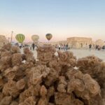 Vivre le Sahara tunisien en 48 heures au départ de Yasmine Hammamet ou de Sousse, c’est possible, confortable et intensément dépaysant. En deux jours, nous combinons routes panoramiques, villages berbères, mer de dunes, balade à dos de chameau au coucher du soleil et nuit en camp saharien sous un ciel que l’on n’oublie jamais. L’itinéraire a été conçu pour maximiser le temps passé sur place tout en gardant un rythme fluide, des pauses photo bien choisies et une logistique claire et sécurisée. Notre objectif : offrir une immersion généreuse, authentique et pleine de petits détails qui font la différence. Pour visualiser d’autres variantes et combiner cette escapade avec un séjour plus long, explorez nos circuits désert sur-mesure . Pourquoi partir du littoral vers le Sahara en 2 jours ? Depuis Yasmine Hammamet et Sousse, la transition vers le Sud tunisien est un voyage en soi. En quittant la côte, la lumière change, les palmeraies s’étirent, les chotts scintillent comme des miroirs et les dunes apparaissent, d’abord timides, puis majestueuses. Sur deux jours, nous visons un équilibre : assez de route pour atteindre les panoramas iconiques, mais suffisamment de temps sur place pour profiter de l’essentiel sans courir. Accessibilité : départ tôt le matin, prise en charge à l’hôtel, itinéraire optimisé, chauffeur francophone. Confort : 4×4 ou minibus climatisé selon la taille du groupe, étapes courtes toutes les 90–120 minutes. Expérience : balade à dos de chameau au coucher du soleil, dîner traditionnel et nuit sous tente dans un camp sélectionné pour sa qualité et son cadre. Souplesse : deux versions du Jour 2 (option Ksar Ghilane ou option Chott El Jerid + Ong Jmel) selon vos envies et la saison. Besoin d’un transfert confortable jusqu’au point de départ ? Notre service de navette aéroport simplifie toute votre logistique. Itinéraire détaillé – Jour 1 : Littoral → Kairouan (selon horaire) → Chott El Jerid → Douz/Matmata → Camp dans les dunes 06:30–07:30 | Départ de Yasmine Hammamet ou Sousse Accueil à votre hébergement, présentation du conducteur-accompagnateur, rappel des points sécurité et du déroulé sur deux jours. Nous partons tôt pour profiter de la lumière du matin et fluidifier les temps de route. (Option courte) Pause Kairouan — café & médina Si l’horaire le permet, arrêt express pour un café maure et une marche légère près de la médina (extérieurs). Cette pause met tout de suite dans l’ambiance des villes caravanières. Fin de matinée | Chott El Jerid Approche du Chott El Jerid, lac salé irréel où les teintes blanches et rosées s’étirent jusqu’à l’horizon. Arrêts photos sur des points sûrs, explications sur la géologie, la luminosité et la formation des mirages. Les mois d’automne et d’hiver offrent souvent la meilleure transparence. Déjeuner | Oase road Pause dans une adresse simple et propre, cuisine locale : salade méchouia, couscous, grillades ou tajine. Nous tenons compte des régimes (végétarien, halal, allergies) annoncés à l’avance. Après-midi | Douz ou Matmata selon la saison Variante Douz : arrivée à la “porte du Sahara”, équipement léger (écharpe/cheche, lunettes, crème solaire), puis liaison vers le camp. Variante Matmata : rapide passage dans un hameau troglodyte (extérieurs), point de vue sur les reliefs lunaires avant de gagner les premières dunes. Golden hour | Balade à dos de chameau & coucher du soleil Accueil par les chameliers, briefing douceur (monter/descendre, rythme), puis file indienne vers un point haut. Au loin, la ligne du soleil se fond dans les vagues de sable. Photos en contre-jour, silhouettes élégantes des dromadaires, calme enveloppant. Soirée | Dîner saharien & veillée sous les étoiles Installation en tente privative (lits, couvertures, tapis tissés). Dîner : soupe chaude aux épices douces, tabouna (pain au feu), couscous ou mechoui, fruits du palmier-dattier, thé à la menthe. Veillée près du feu : percussions légères, histoires nomades et observation des constellations quand le ciel est dégagé. La nuit au désert est silencieuse, pure, inoubliable. Envie d’allonger l’itinérance un autre week-end ? Parcourez nos circuits désert personnalisables . Nuit en camp saharien : confort mesuré, authenticité maximale Nos camps partenaires privilégient la sobriété élégante : tentes en toile robuste, literie propre et confortable, éclairage doux. Les espaces communs sont pensés pour le repos et l’observation du ciel. Nous attachons une importance particulière à la gestion de l’eau et des déchets, au respect du site et au bien-être animal. Les chameaux évoluent à un rythme régulier, les charges sont contrôlées, et les pauses sont prévues. Hygiène & sécurité : trousse de premiers secours, eau minérale pendant les activités, briefing clair. Ambiance : pas de sono agressive, l’idée est de laisser parler le désert. Options : tente premium (surface et literie supérieures), privatisation partielle pour familles, gâteau d’occasion, session photo au coucher/lever. Pour diversifier vos expériences actives autour de l’oasis et des reliefs, découvrez aussi nos idées plein air : randonnée montagne & Sahara . Itinéraire détaillé – Jour 2 : Lever du soleil → Module au choix → Retour littoral Aube | Lever du soleil sur les crêtes Réveil avant l’aube, thé brûlant, marche douce ou balade à dos de chameau vers un belvédère. Les teintes pastel se succèdent, le sable rosit, l’air est vif et cristallin. Petit-déjeuner au camp au retour (galettes, miel, fromages, olives, œufs). Choisissez votre Module Jour 2 (en fonction de la saison et des envies) Module A – Ksar Ghilane : oasis, sources chaudes & piste douce Route vers Ksar Ghilane, oasis emblématique aux palmiers serrés, célèbre pour son bassin naturel alimenté par une source. Possibilité de bain (selon météo), marche dans les palmeraies, ou boucle piste facile en 4×4 le long de l’erg. Déjeuner sur place (cuisine locale). Selon l’heure, retour par la piste roulante puis route vers la côte. Module B – Chott El Jerid & Ong Jmel : mirages et reliefs de cinéma Route vers les points de vue du Chott El Jerid pour saisir la lumière de la matinée (différente du Jour 1), puis détour vers Ong Jmel : formations rocheuses et dunes au relief sculptural. Célèbre pour certains décors de cinéma, le site est idéal pour des panoramas grand angle. Déjeuner en route. Retour l’après-midi vers Sousse ou Yasmine Hammamet avec pauses régulières. Fin de journée | Retour à l’hôtel Arrivée prévue en fin d’après-midi / début de soirée, en fonction du module choisi et du trafic. Nous déposons à votre hébergement ou au point convenu. Ce qui est inclus (et ce qui peut s’ajouter) Inclus Prise en charge à Yasmine Hammamet/Sousse et retour. Transport en véhicule climatisé (4×4 ou minibus) avec chauffeur-accompagnateur. Balade à dos de chameau au coucher (et/ou au lever, selon module). Nuit en camp saharien (tente privative), dîner traditionnel et petit-déjeuner. Eau minérale pendant les activités, assistance de base. En option Navette aéroport ou transferts spécifiques : réservez via notre service de navette aéroport . Photographe dédié, privatisation de camp, tente premium. Bain à Ksar Ghilane (selon saison), quad (encadré) si ouvert et autorisé. Assurance voyage personnelle (fortement recommandée). Conseils pratiques : quoi emporter, comment s’habiller, petites astuces Tenue : pantalon léger, couche chaude (polaire) pour la nuit, coupe-vent. Chaussures : fermées ou sandales de marche avec bonne semelle. Accessoires : écharpe/cheche, lunettes de soleil, crème solaire, baume à lèvres, chapeau. Tech : lampe frontale, batterie externe, sac pour protéger appareil photo/smartphone de la poussière. Santé : petite trousse perso, hydratation régulière, collations si besoin. Étiquette saharienne : respectez les indications du guide, ne laissez aucune trace, suivez le rythme du groupe. Météo & meilleures périodes pour partir Octobre à avril : températures idéales pour marcher et profiter des feux de camp. Les nuits peuvent être fraîches : prévoyez une couche chaude. Mai & septembre : plus chaud, nous adaptons les horaires pour viser les golden hours et éviter les pics thermiques. Été : possible, mais format ajusté (plus de fin de journée et nuit, si la météo le permet). En toute saison, la lumière fait le spectacle ; l’hiver offre souvent les ciels étoilés les plus profonds. Tourisme responsable & respect du désert Nous tenons à une approche responsable qui valorise les communautés locales et préserve l’équilibre fragile du Sahara : Groupes à taille humaine, espaces de campement définis, zéro plastique quand c’est possible. Rémunération équitable des chameliers et partenaires locaux. Bien-être animal : charges contrôlées, pauses régulières, pas de sollicitations excessives. Économie locale : cuisine de saison, artisanats des oasis, circuits courts. Variantes & extensions : prolongez l’aventure Vous avez adoré ces 48 heures au désert ? Prolongez par une rando à la journée ou 2–3 jours dans les reliefs et oasis de montagnes : Chebika, Tamerza, crêtes et canyons des montagnes du Sahara. Nous proposons des itinéraires actifs et photogéniques : 👉 Inspirez-vous de nos suggestions Randonnée montagne & Sahara . Vous pouvez aussi explorer d’autres boucles désert : 👉 Parcourez nos circuits dans le désert et composez votre roadbook idéal. FAQ – 2 jours d’exploration du Sahara au départ de Yasmine Hammamet/Sousse Faut-il être sportif pour monter à dos de chameau ? Non. Le rythme est doux, la montée/descente se fait avec aide. Nous adaptons la durée selon vos préférences. Peut-on voyager avec des enfants ? Oui. Nous ajustons les pauses, le temps à dos de chameau et proposons des tentes communicantes pour les familles. Quelles sont les installations au camp ? Tentes privatives, literie propre, espace repas, sanitaires simples. Éclairage doux ; prévoir batterie externe pour la recharge. Et si le vent se lève ? Le guide adapte l’itinéraire pour rester confortables et en sécurité. En cas de météo défavorable, report ou alternatives. Puis-je privatiser l’expérience ? Oui : privatisation partielle ou totale, dîner d’occasion, scénographie (anniversaire, demande, shooting). Combien d’heures de route par jour ? Selon la variante, 5 à 7 h avec pauses régulières. Nous optimisons pour garder une vraie immersion sur place. Réserver, avis et devis gratuit Prêts pour une parenthèse saharienne au départ de Yasmine Hammamet/Sousse ? Comparez les itinéraires, modules et durées sur nos circuits désert . Demandez un devis personnalisé (gratuit) avec vos dates, taille de groupe et options : devis voyage désert – Tunisie . Laissez un avis ou lisez les retours de nos voyageurs : page TripAdvisor officielle . Besoin d’un transfert arrivée/départ totalement simplifié ? Notre navette aéroport s’occupe de tout. Vous souhaitez étirer l’aventure sur 3 ou 4 jours, avec plus de marche et de panoramas ? Parcourez aussi nos idées randonnée montagne & Sahara et composez une boucle complète Sud tunisien. Récapitulatif rapide du programme (indicatif) Jour 1 : Départ Yasmine Hammamet/Sousse tôt → Chott El Jerid (arrêts photo) → Douz / Matmata → balade à dos de chameau au coucher du soleil → dîner & nuit en camp saharien. Jour 2 : Lever du soleil (marche douce ou chameau) → Module A Ksar Ghilane (oasis & bain) ou Module B Chott + Ong Jmel (panoramas & dunes) → retour à la côte en fin d’après-midi. Chaque départ est traité avec soin, dans un format “nous”, une logistique claire, et le souci du détail qui rend cette aventure simple à vivre, riche à raconter et belle à photographier.