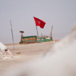 Quand on rêve d’un désert vrai, d’une lumière qui caresse les dunes et d’une nuit d’étoiles au silence enveloppant, il faut aller droit à l’essentiel : une échappée de 2 jours / 1 nuit sous tente bédouine dans le Sahara du Sud tunisien. Nous organisons un court séjour intensément riche, pensé pour ceux qui veulent vivre le désert sans compromis : transferts fluides, étapes emblématiques, cuisine du feu de bois, sécurité maîtrisée, et ce petit supplément d’âme qu’on ne trouve que chez des passionnés du Sud. Explorez nos programmes complets ici : Circuits désert – SudTunisie.com . Un format court, des émotions grandes : pourquoi ce circuit 2 jours / 1 nuit séduit tant Deux jours suffisent pour goûter à l’essentiel : la traversée du Chott El-Jérid vers Douz, la balade à dos de dromadaire au coucher de soleil, un bivouac authentique à Ksar Ghilane ou dans l’erg voisin, le réveil au thé fumant face aux premières lueurs, puis la remontée vers les oasis de montagne ou les villages troglodytes. Le rythme est cadencé sans être pressé, les temps forts s’enchaînent, les paysages changent, et la mémoire retient la chaleur du sable, les voix autour du feu et le parfum du pain de sable qu’on partage. Accessible : départs depuis Tunis, Hammamet, Sousse, Monastir, Sfax, Djerba, Gabès, Bizerte, Kélibia et Korba. Flexible : variantes selon la saison, vos envies (plus d’oasis, plus de dunes, touche sportive, visite artisanale). Clé en main : transferts, 4×4 climatisés, campement, repas, encadrement local de confiance. Sans fausses notes : horaires optimisés pour les golden hours et l’évitement des pics de chaleur. Tout pour vous simplifier la vie : transferts aéroport sur demande avec notre navette aéroport . Jour 1 – Chott, Douz et dunes dorées : la porte du Sahara s’ouvre Transfert matinal depuis votre ville de départ Tôt le matin, nous venons vous chercher à Tunis, Hammamet, Sousse, Monastir, Sfax, Djerba, Gabès, Bizerte, Kélibia ou Korba. Mise en route fluide, briefing sur l’itinéraire, hydratation, arrêts photo. Ceux qui arrivent par avion profitent d’un accueil personnalisé via notre service de navette aéroport . Le Chott El-Jérid : le grand miroir du Sud L’immense Chott El-Jérid déploie sa blancheur laiteuse et ses mirages mouvants. Nous marquons une pause photo aux meilleurs points de vue pour capter les reflets, comprendre la géologie du lieu et glisser un premier récit saharien. Les voyageurs nous disent souvent que ce “silence blanc” ancre déjà le voyage. Douz, la porte du désert À Douz, les dunes ondulent et l’air change de texture. Selon la saison et votre envie, deux voies s’offrent à nous : Cap sur l’erg pour un coucher de soleil à dromadaire et une première immersion dans le sable. Ou déjeuner terroir en ville avant de reprendre la piste vers le campement choisi. Ksar Ghilane ou erg confidentiel : la magie du bivouac Le cœur du séjour, c’est la nuit sous tente. À Ksar Ghilane, l’oasis scintille, la source chaude invite au bain, la piste vers le fort en option (quad/4×4) aiguise le sens de l’aventure. Selon météo et saison, nous sélectionnons le campement le plus adapté : intimiste, confortable, respectueux du lieu. Au programme : Coucher de soleil sur les dunes (à pied, dromadaire ou 4×4). Dîner saharien : couscous ou tajine, pain de sable, dattes de Tozeur, thé à la menthe. Veillée : contes bédouins, initiation au ciel étoilé, temps pour soi. Nuit sous tente : couchage préparé, encadrement discret, sécurité supervisée. Pour des idées voisines ou un séjour plus long, parcourez nos circuits désert et nos excursions en Tunisie . Jour 2 – Lueurs de l’aube, oasis et troglodytes : retour avec l’âme légère Aube sur les dunes et petit-déjeuner nomade Le lever du soleil est un rituel : couleurs pastel, air frais, premiers pas dans le sable encore froid. Nous servons un petit-déjeuner nomade (pain chaud, confitures, olives, œufs/omelette, fruits, café/thé) avant de replier le camp en douceur. Bain à la source, piste et panoramas Si vous avez dormi à Ksar Ghilane, une dernière baignade dans la source chaude prolonge la détente. Nous reprenons ensuite la piste en direction de Matmata ou des oasis de montagne selon votre préférence et l’option retenue au devis. Option 1 : Matmata, les maisons troglodytes Les habitants creusés dans l’argile préservent une fraîcheur étonnante. Visite guidée, rencontre avec une famille, dégustation d’huile d’olive, explications sur la construction traditionnelle. Les paysages ondulent, presque lunaires ; l’étape est dépaysante et culturelle. Option 2 : Chebika, Tamerza, Mides – les oasis accrochées à la montagne Direction Tozeur et ses oasis de montagne. À Chebika, la source jaillit en terrasse ; Tamerza dévoile ses cascades et Mides ses gorges. Marche douce à l’ombre des palmiers, panoramas exceptionnels, photographie à profusion. Pour les amateurs de marche, prolongez l’inspiration avec nos programmes randonnée montagne Sahara . Retour vers votre ville d’arrivée Nous ajustons les horaires de retour à votre vol/train/séjour balnéaire. La boucle est bouclée, le désert reste. Pour prolonger le voyage depuis votre canapé, explorez notre blog d’excursions en Tunisie . Ce qui est inclus – et ce qui peut s’ajouter sans alourdir l’esprit Inclus par défaut : Transferts aller/retour depuis Tunis, Hammamet, Sousse, Monastir, Sfax, Djerba, Gabès, Bizerte, Kélibia, Korba (selon devis). 4×4 climatisé avec chauffeur-guide francophone. Bivouac sous tente (équipement, sanitaires selon camp). Dîner au camp, petit-déjeuner du lendemain. Balade à dromadaire au coucher ou au lever (selon timing). Assistance 24/7 et brief sécurité. Options fréquentes (sur demande) : Bain thermal et temps libre prolongé à Ksar Ghilane. Quad vers le fort (encadrement local, supplément). Camp premium (tente plus spacieuse, literie améliorée). Déjeuner terroir supplémentaire jour 1 ou 2. Extension 1 jour vers Tozeur et les oasis de montagne, ou Matmata–Tataouine–Chenini. Pour un chiffrage clair et rapide : devis gratuit / contact . Conseils ultra-pratiques pour 48 h parfaites dans le Sahara Saisons : printemps/automne idéaux ; hiver lumineux (nuits fraîches) ; été possible avec horaires early & late et siestes ombragées. Tenue : manches longues légères, pantalon fluide, chèche/casquette, veste chaude pour la nuit, chaussures fermées. Santé : hydratez-vous régulièrement ; lunettes anti-UV, crème solaire, stick lèvres ; mini-trousse (pansements, soluté réhydratant). Photo : batteries chargées, chiffon doux, housses zippées anti-sable ; doré du matin/soir = photos inratables. Respect : on emporte ses déchets, on reste sur les traces, on préserve les points d’eau. Esprit SudTunisie.com : sécurité, éthique, hospitalité Nous bâtissons des expériences responsables : Guides et chauffeurs rémunérés équitablement, partenariats locaux durables. Itinéraires adaptés aux conditions du jour (météo, vent, température). Matériel vérifié et brieﬁng sécurité systématique. Cuisine locale : produits du terroir, alternatives végétariennes/vegan sur demande. Transmission : histoires de piste, géologie du Chott, savoir-faire du pain de sable, lecture du ciel. Envie d’avis concrets ? Consultez les retours de nos voyageurs : Sud Tunisie – TripAdvisor . Varier les plaisirs : idées d’extensions et d’itinéraires cousus main Oasis de montagne en version rando douce (ponts de pierre, bassins, gorges) : jetez un œil à nos formats randonnée montagne Sahara . Journée bonus autour des ksour (greniers fortifiés) et des villages perchés : Chenini, Douiret, Tataouine. Grand panorama en 3–4 jours : Tozeur – Chott – Douz – Ksar Ghilane – Matmata, idéal si vous avez un week-end prolongé. Escapades thématiques : photo, gastronomie, astronomie, artisanat (poterie, cuir, tissage). Pour des idées en continu et des récits inspirants : Blog – excursions Tunisie . Pour comparer nos formats courts : Excursion en Tunisie . Pour la vue d’ensemble de nos programmes : Circuits désert . Départs garantis depuis les grandes villes : simplicité et ponctualité Nous avons pensé la logistique pour que tout soit simple : Prise en charge depuis Tunis, Hammamet, Sousse, Monastir, Sfax, Djerba, Gabès, Bizerte, Kélibia, Korba. Horaires optimisés pour épouser les plus belles lumières. Retour flexible selon votre vol/train. Transferts aéroport sur demande via navette aéroport . Assistance 24/7 : nous restons joignables, nous ajustons si besoin. Votre feuille de route pour réserver en 3 étapes Inspirez-vous : parcourez nos pages circuits désert , excursions en Tunisie et randonnée montagne Sahara . Faites-nous part de vos envies (dates, ville de départ, camp souhaité, rythme, options) via le devis gratuit / contact . Validez : nous verrouillons les étapes, réservons le camp, envoyons le roadbook et, si besoin, vos transferts navette aéroport . Exemple d’itinéraire détaillé – “2 jours / 1 nuit sous tente” Jour 1 06:00–07:30 : départ (selon ville), briefing, pause café en route. Matinée : Chott El-Jérid – arrêts photo, explications. Midi : arrivée Douz, déjeuner terroir (selon timing). Après-midi : piste vers Ksar Ghilane ou erg confidentiel ; installation au camp. Fin de journée : balade à dromadaire et coucher de soleil sur les dunes. Soirée : dîner saharien, pain de sable, veillée (contes & étoiles), nuit sous tente. Jour 2 Aube : réveil doux, lever de soleil, thé/café. Matin : bain à la source (si Ksar Ghilane), pistes de retour. Fin de matinée / midi : Matmata (maisons troglodytes) ou Chebika–Tamerza–Mides (marche douce). Après-midi : retour vers votre ville d’arrivée (horaires ajustés à vos impératifs). Variantes : quad encadré au fort (supp.), camp premium, déjeuner supplémentaire, extension 1 jour vers Tozeur ou Tataouine–Chenini. Les détails finaux (ordre des étapes, horaires) sont personnalisés au moment du devis gratuit . Nos engagements : clarté, confort, sécurité, respect Clarté : un devis transparent, pas de surprises. Confort : véhicules entretenus, campements choisis, literie propre, cuisine soignée. Sécurité : guides formés, itinéraires adaptés, plan météo, trousse de secours. Respect : gestes éco-responsables, économie locale soutenue, partage sincère. Les avis parlent d’eux-mêmes : Sud Tunisie – TripAdvisor . Prêt·e à vivre votre nuit d’étoiles ? Le désert ne se raconte pas, il se vit : 48 heures suffisent pour inscrire un souvenir qui dure longtemps. Avec SudTunisie.com, vous voyagez l’esprit léger, entouré d’une équipe locale qui connaît chaque piste, chaque oasis, chaque souffle de vent. Vue d’ensemble : Circuits désert Formats courts & sur-mesure : Excursion en Tunisie Versions “marche & panoramas” : Randonnée montagne Sahara Idées, récits, conseils : Blog – excursions Tunisie Transferts fluides : Navette aéroport Chiffrage clair : Devis gratuit / contact Retours voyageurs : Avis TripAdvisor Sud Tunisie 2 jours / 1 nuit sous tente : un programme court, des sensations grandes, et cette certitude au retour d’avoir touché quelque chose d’essentiel.